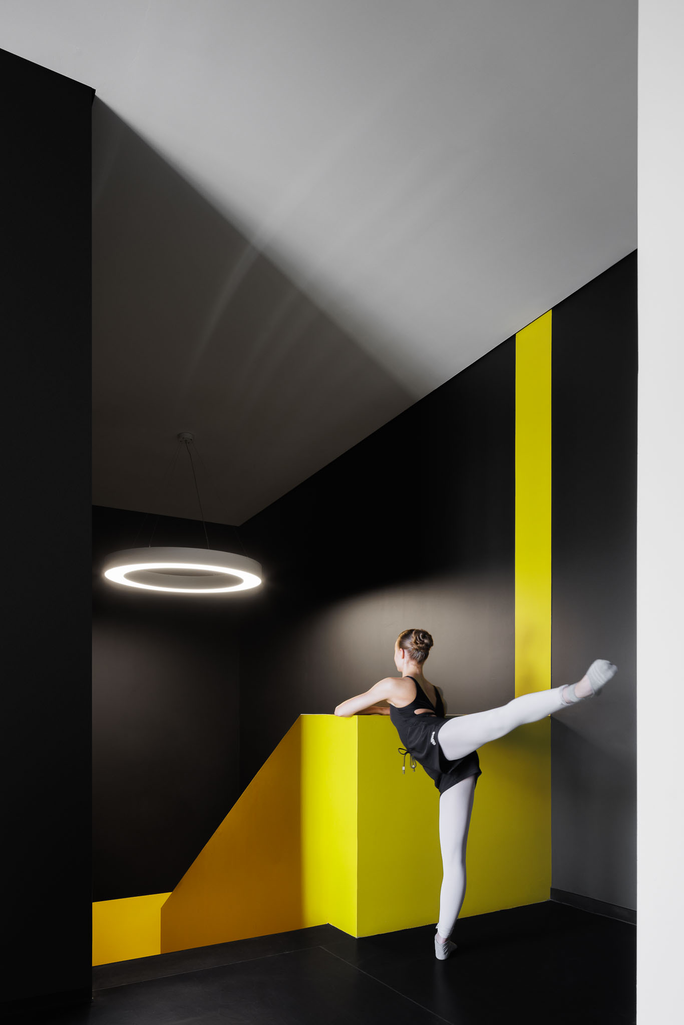 Escadas: Escadas pretas com paredes amarelas e pretas, com candeeiro circular suspenso. — Clínica de fisioterapia - Fisiminho arquitetura L2C Arquitetura em Braga