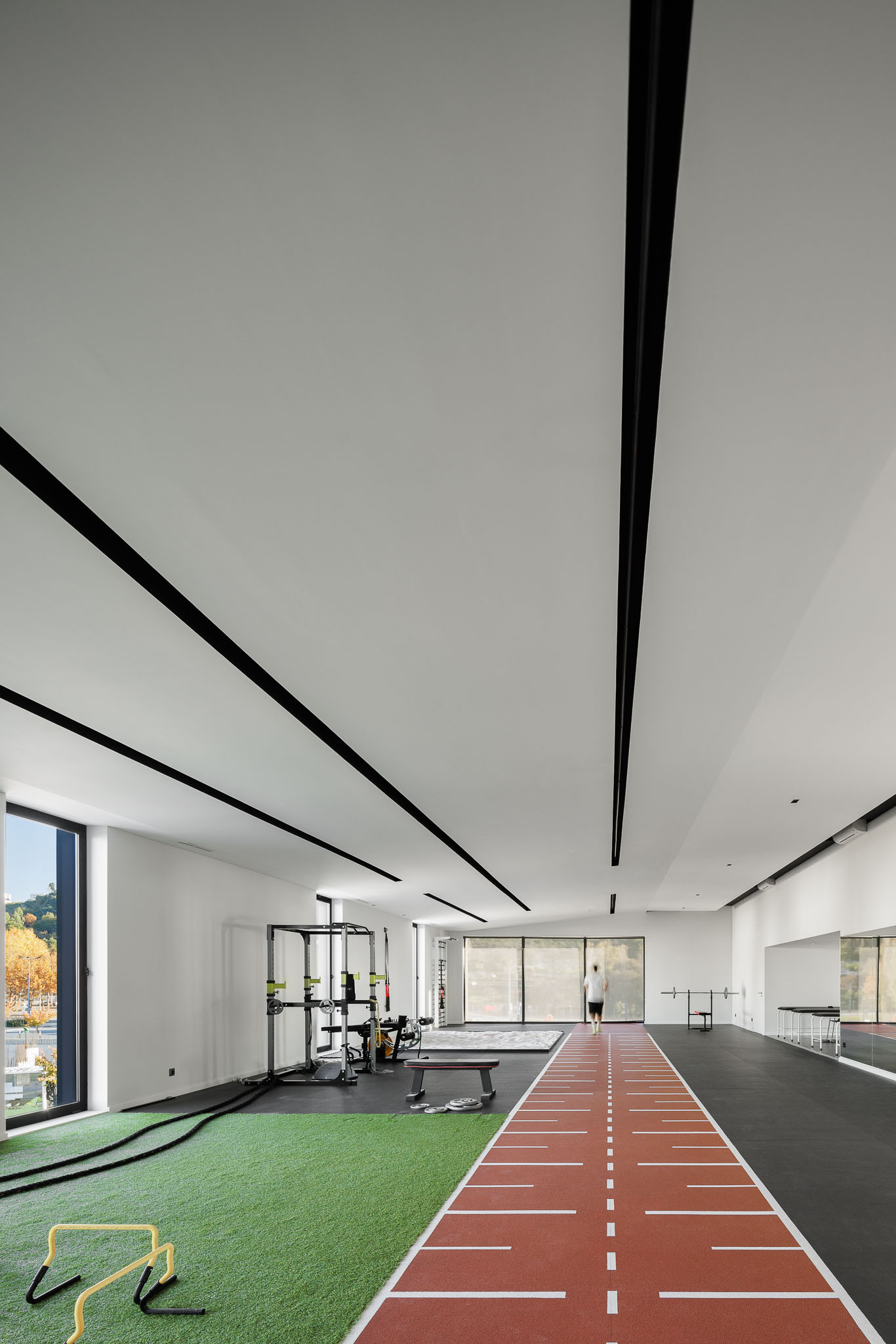 Ginásio: Espaço amplo com relva sintética, pista de atletismo e equipamentos de treino. — Clínica de fisioterapia - Fisiminho arquitetura L2C Arquitetura em Braga