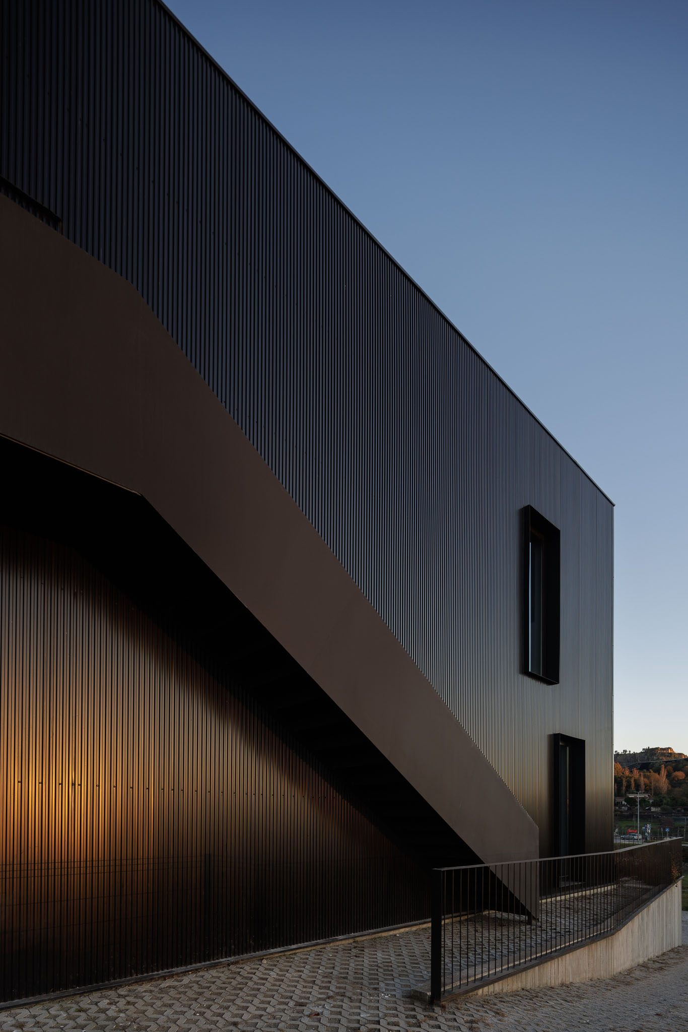 Fachada: Detalhe de escadas exteriores em metal preto e revestimento metálico. — Clínica de fisioterapia - Fisiminho arquitetura L2C Arquitetura em Braga