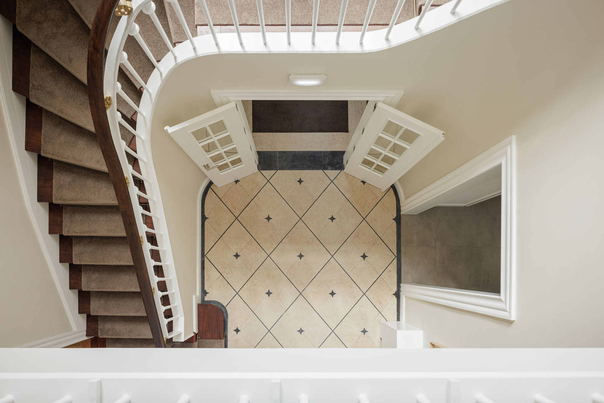 Hall de entrada: Vista superior da escadaria, pavimento em mosaico e porta envidraçada. — Casa Kala arquitetura Ren Ito em Porto