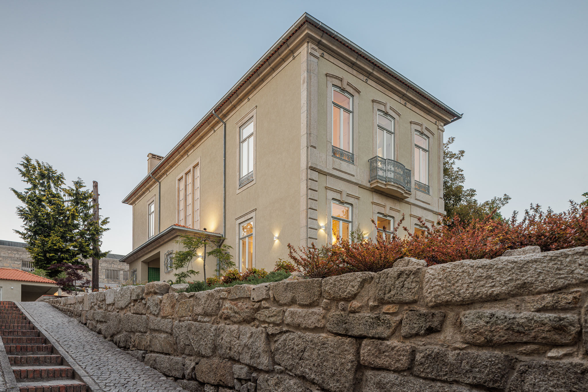 Exterior: Vista lateral da casa com jardim e escadaria de acesso. — Casa Kala arquitetura Ren Ito em Porto