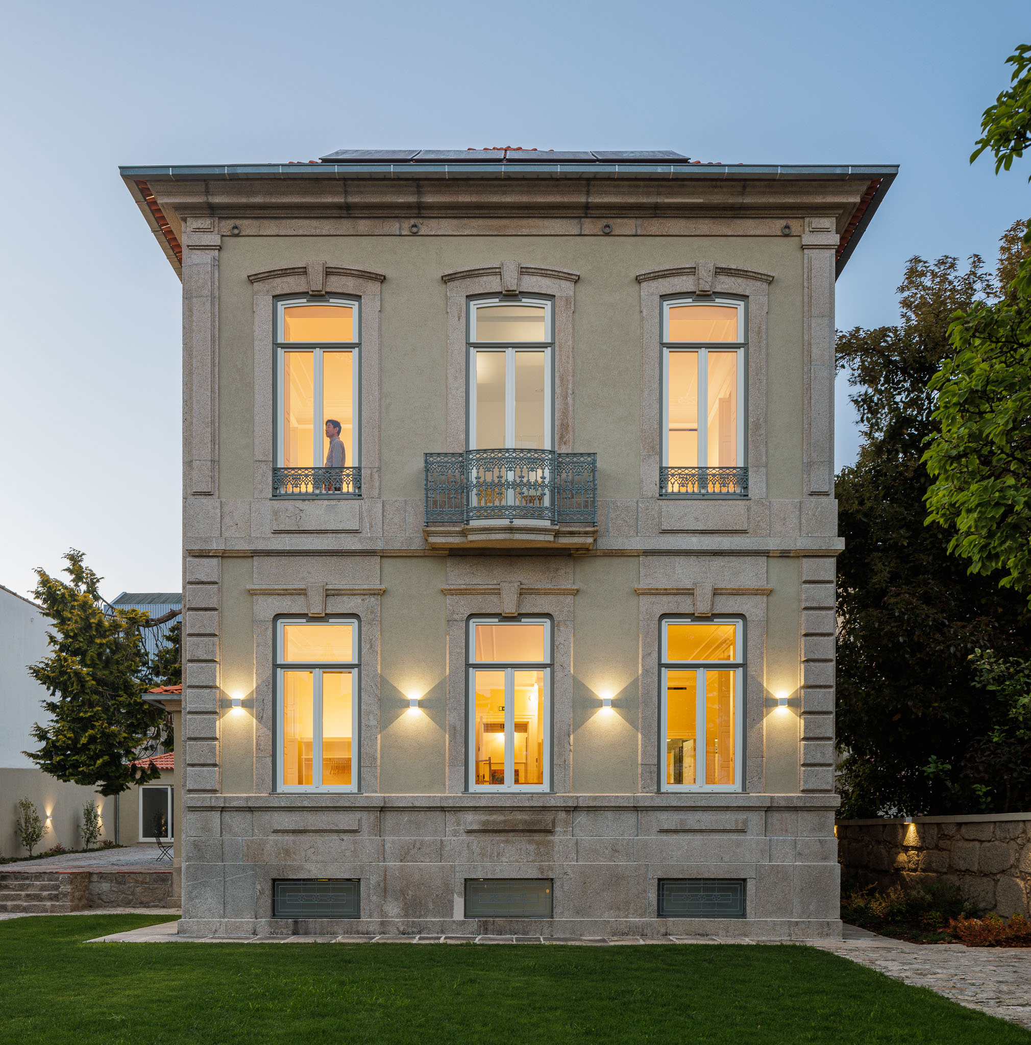 Exterior: Fachada principal da casa com jardim relvado e céu azul. — Casa Kala arquitetura Ren Ito em Porto