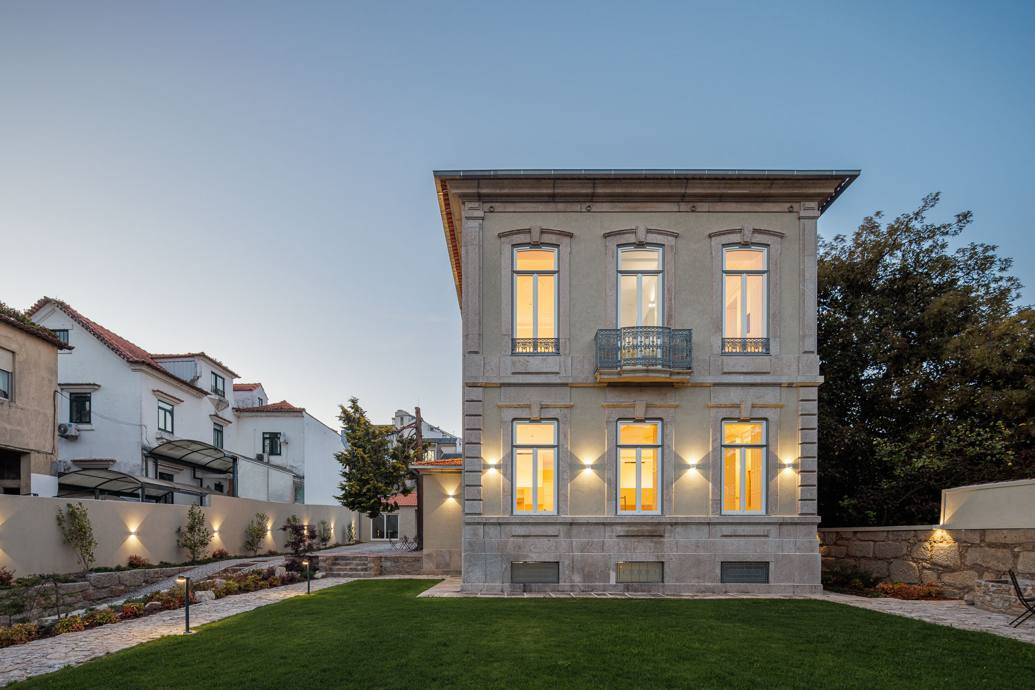 Exterior: Vista lateral da casa com jardim relvado e céu azul. — Casa Kala arquitetura Ren Ito em Porto