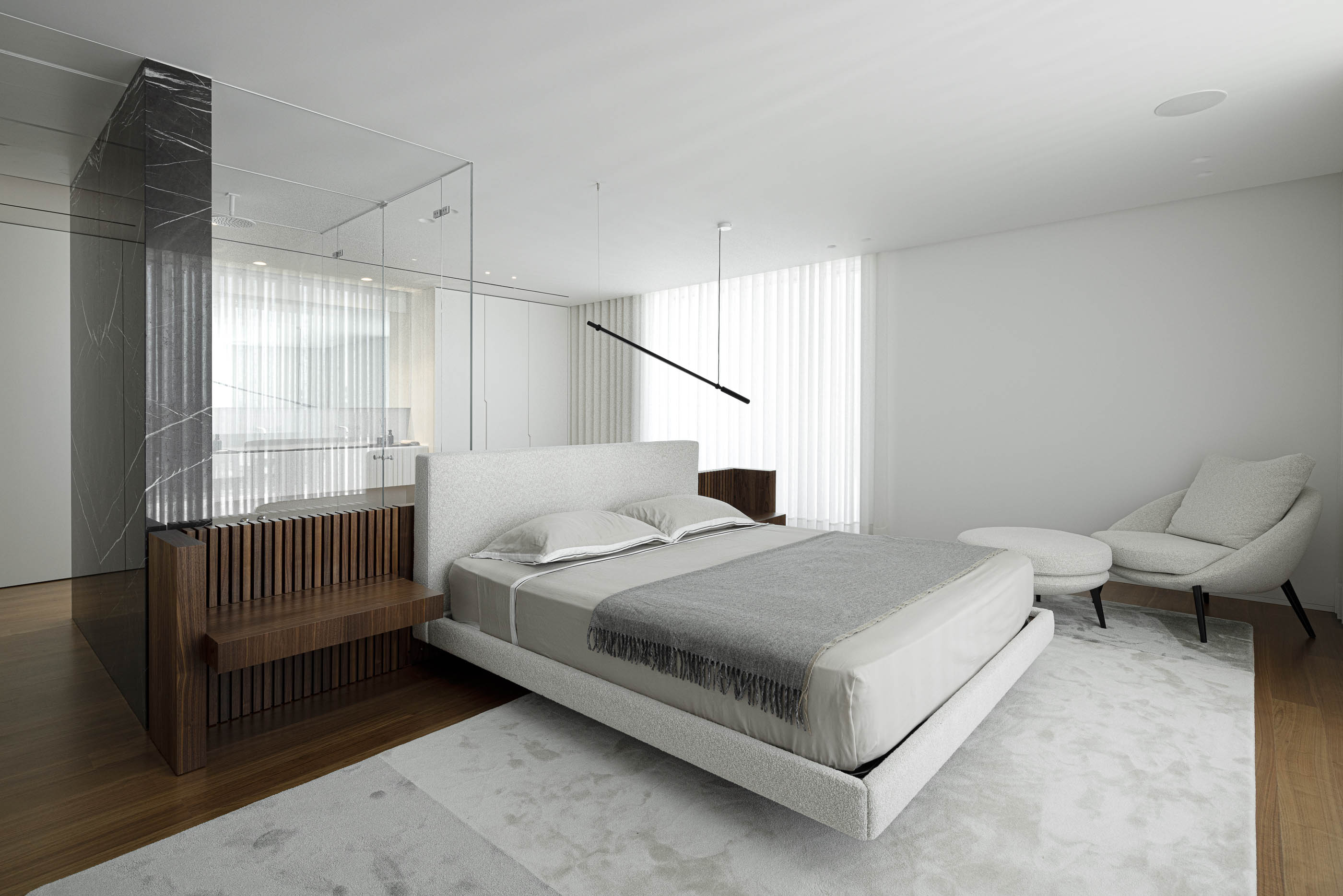 Quarto: Cama com cabeceira texturizada, divisória em mármore e casa de banho integrada. — Riscowhite arquitetura Risco Singular em Barcelos