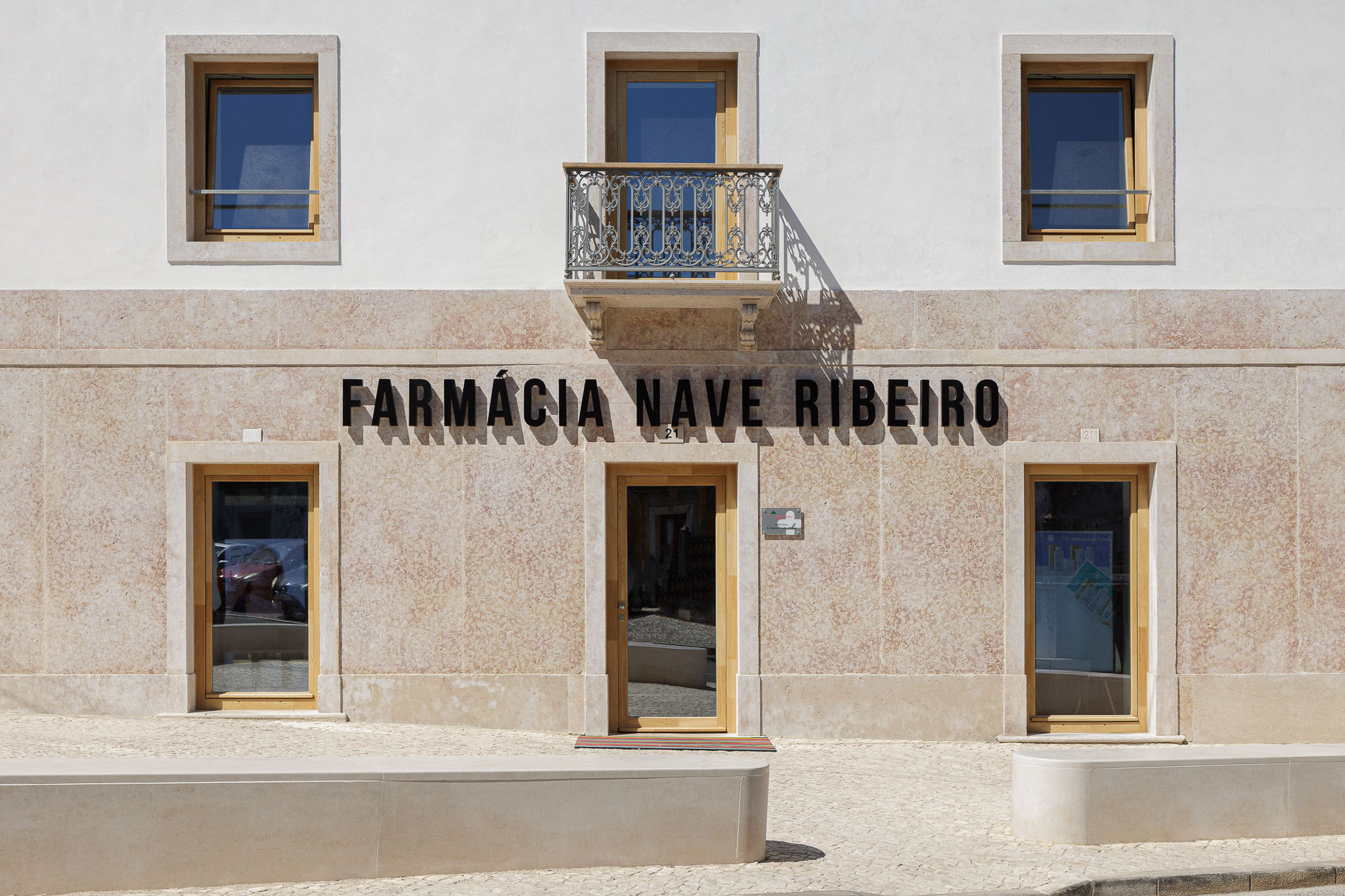 Fachada: Vista frontal da farmácia com nome em letras pretas, janelas em madeira e varanda ornamentada. — Farmácia NR arquitetura Esquissos Arquitectura em Sintra