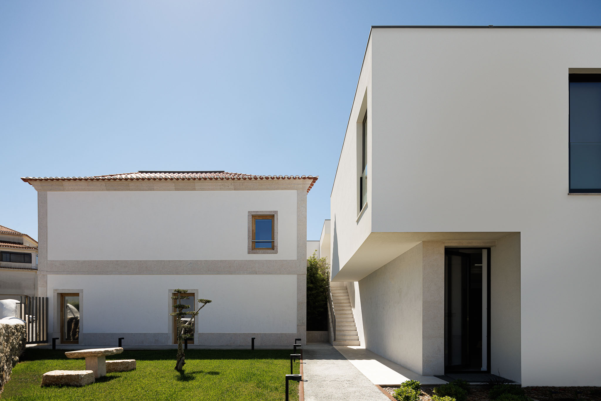 Exterior: Vista do jardim com relvado, caminho em gravilha, e edifícios com arquitetura tradicional e moderna. — Farmácia NR arquitetura Esquissos Arquitectura em Sintra