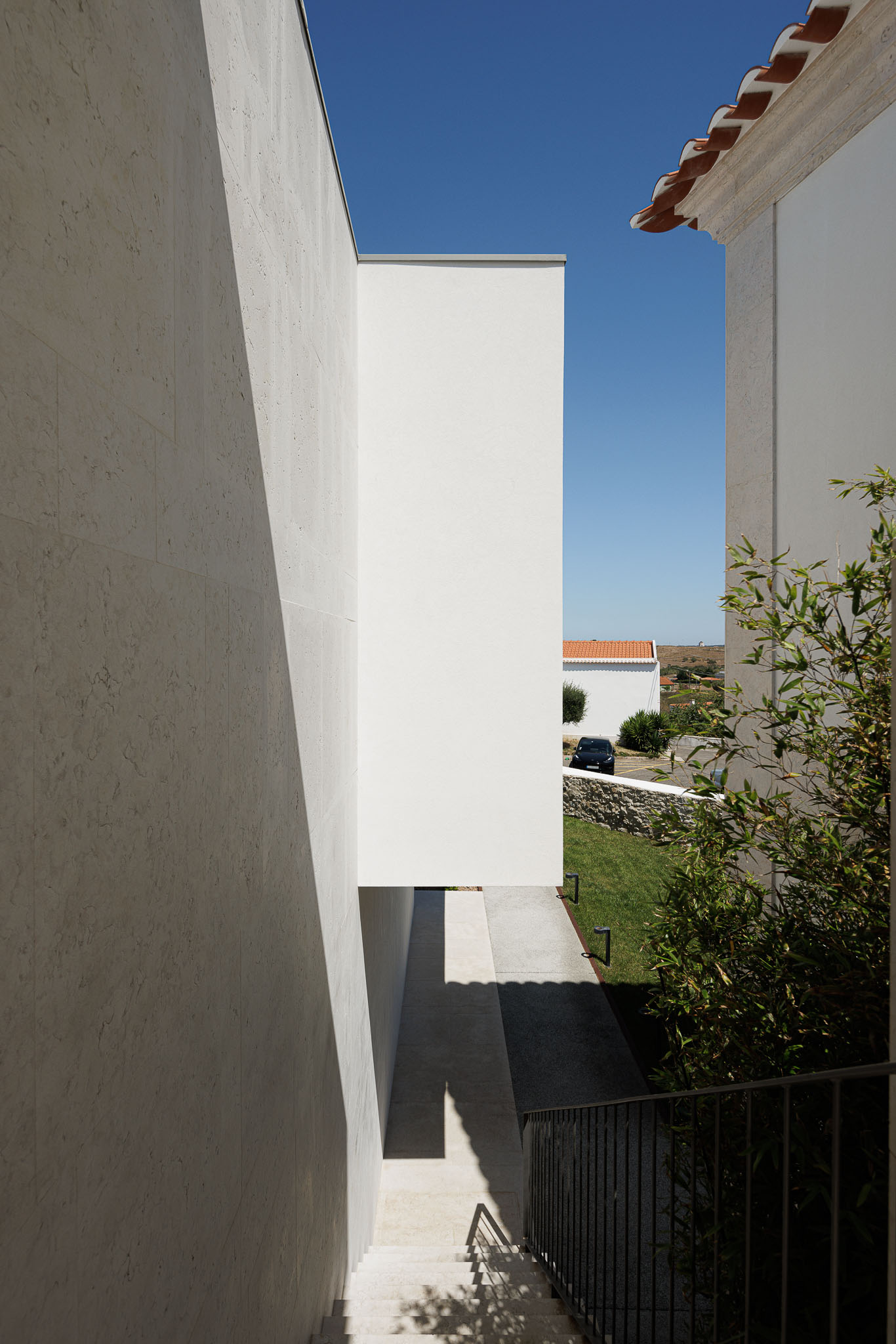Exterior: Escadas exteriores com corrimão metálico, ligando edifícios com revestimentos distintos. — Farmácia NR arquitetura Esquissos Arquitectura em Sintra