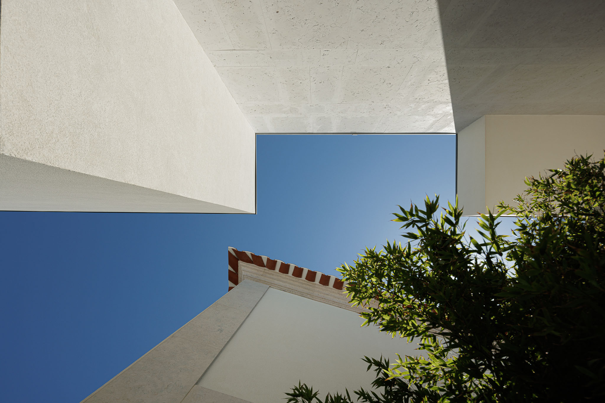 Exterior: Vista para o céu emoldurada por edifícios com diferentes revestimentos e vegetação. — Farmácia NR arquitetura Esquissos Arquitectura em Sintra