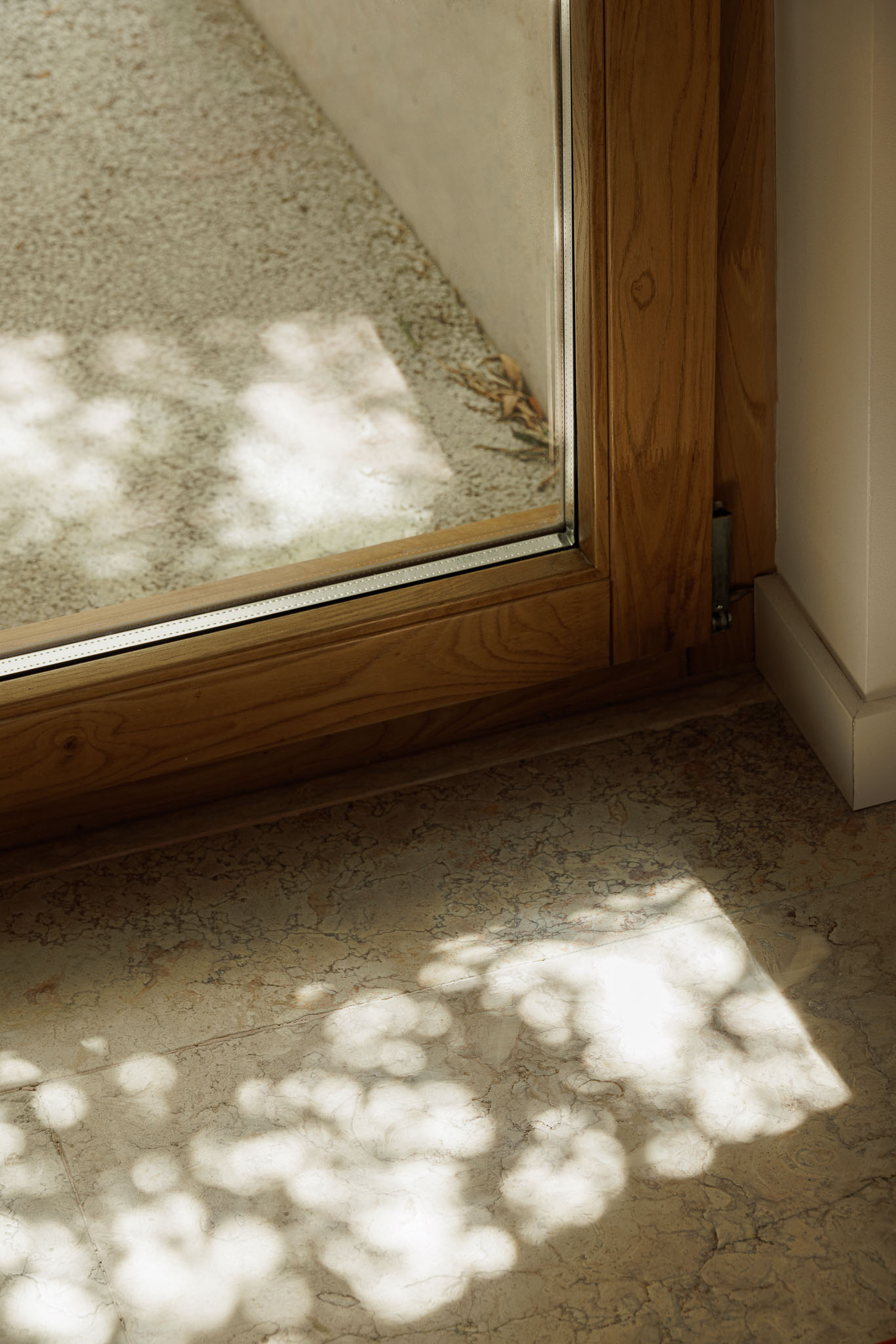 Interior: Detalhe do pavimento em pedra clara e caixilharia em madeira, com luz natural. — Farmácia NR arquitetura Esquissos Arquitectura em Sintra