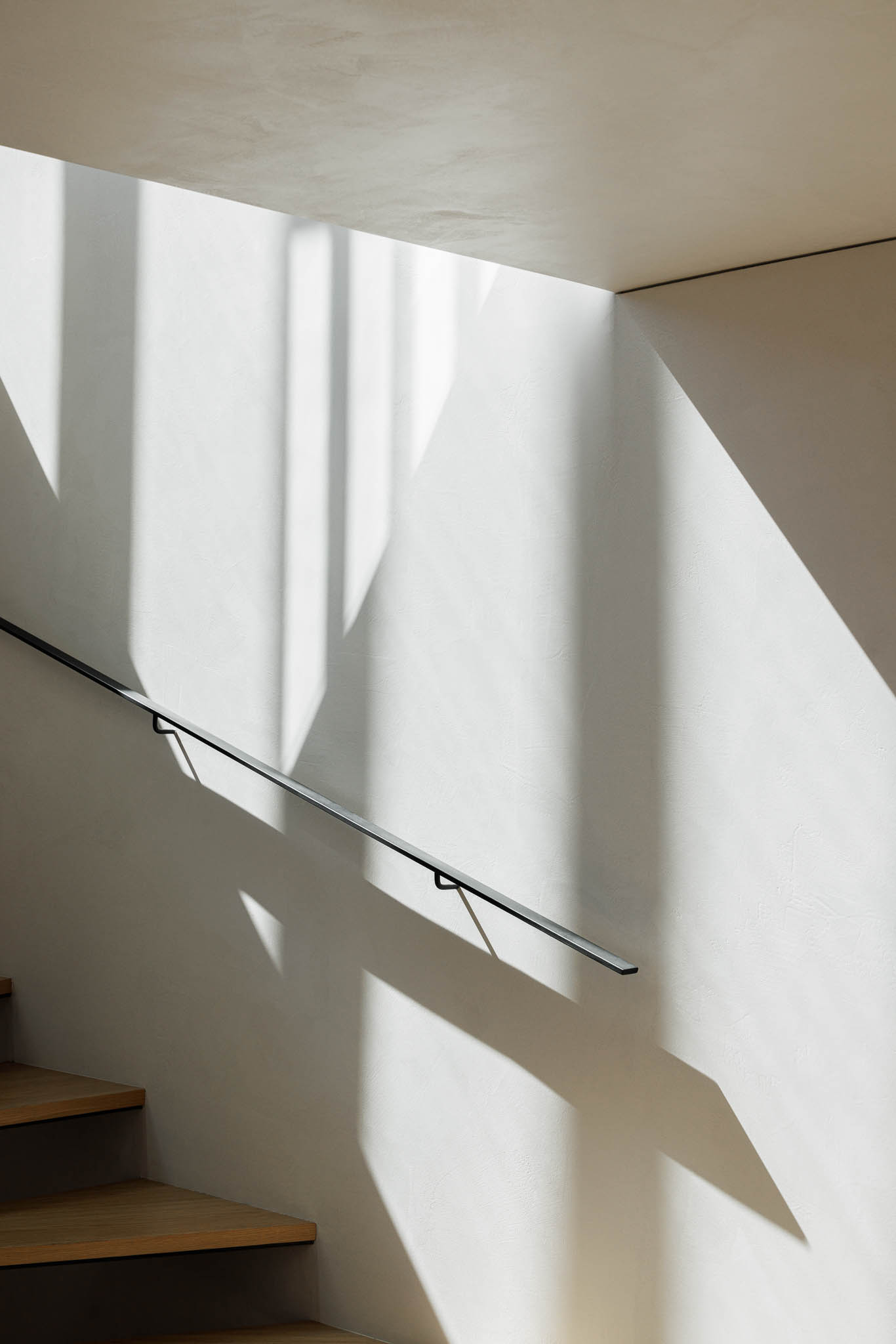 Escadas: Detalhe da escada interior com degraus em madeira e corrimão preto, iluminada por luz natural. — Casa de Bouro arquitetura Mutant Architecture and Design em Terras de Bouro