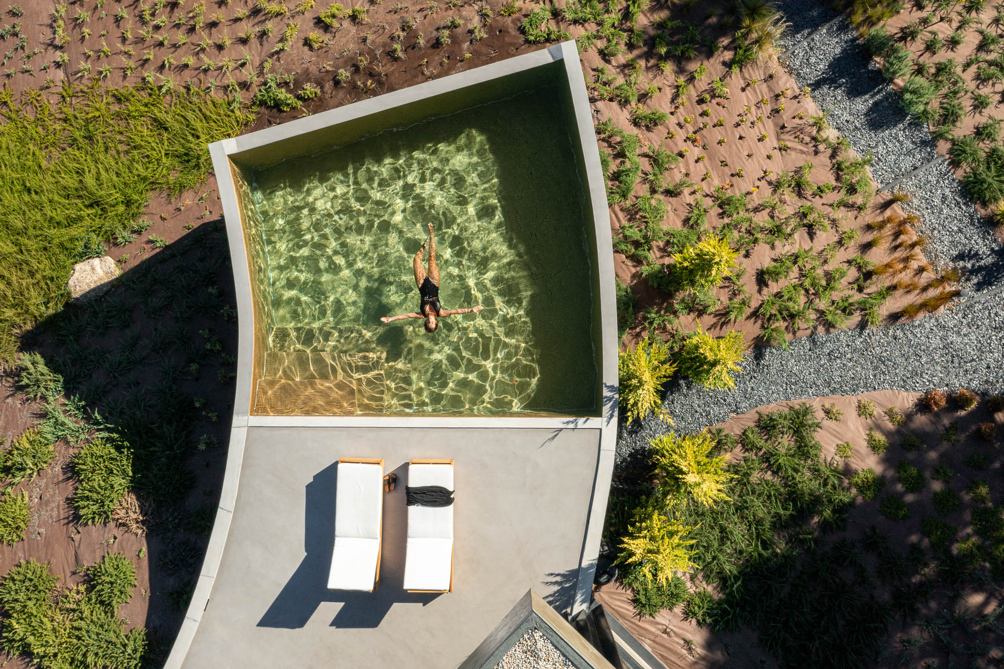 Exterior: Vista aérea da piscina infinita, espreguiçadeiras e jardim com vegetação rasteira. — Casa de Bouro arquitetura Mutant Architecture and Design em Terras de Bouro