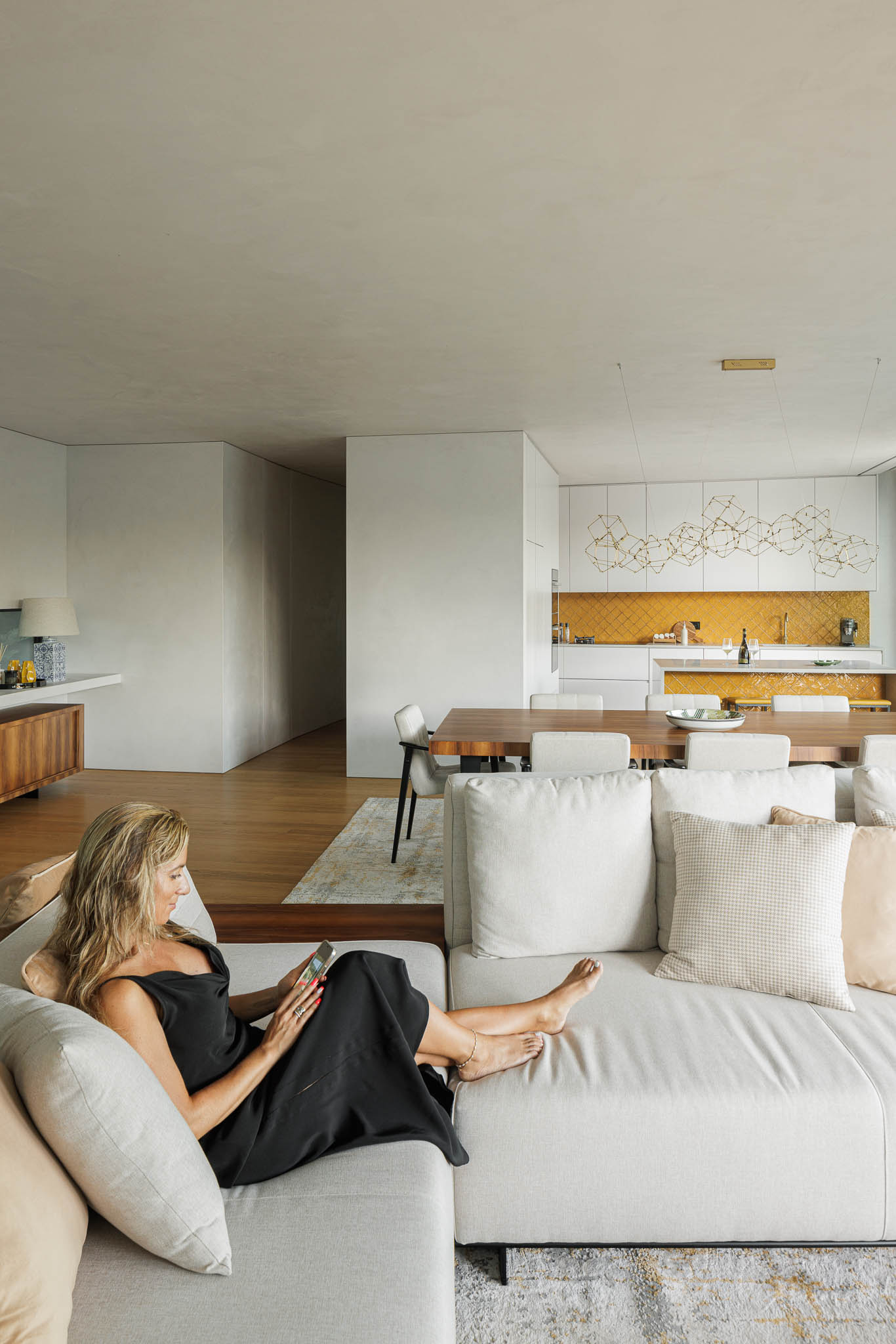 Sala de estar: Sala de estar com sofá branco e vista para a cozinha e sala de jantar. — Casa de Bouro arquitetura Mutant Architecture and Design em Terras de Bouro