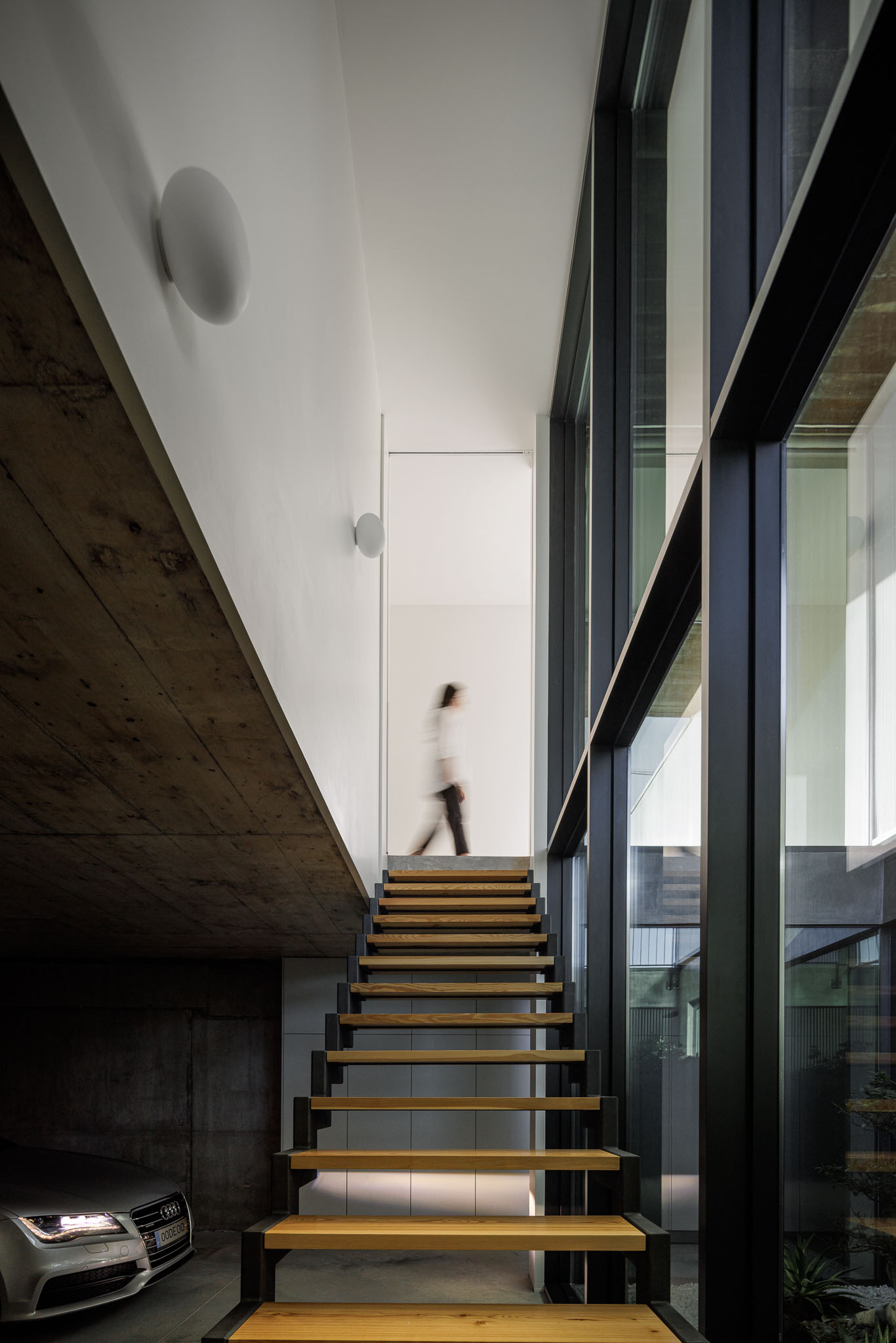Escadaria: Escadas em madeira e metal, com iluminação natural através de janelas amplas. — Casa Ponte arquitetura stu.dere em Amarante
