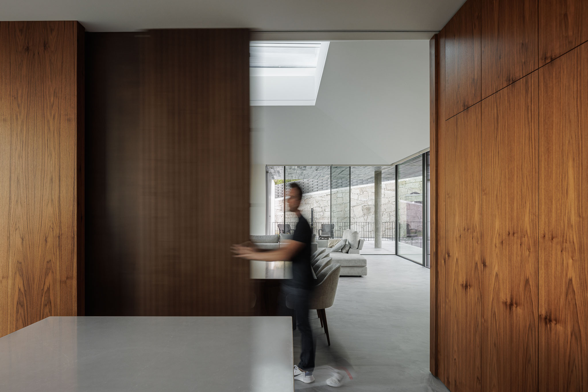 Cozinha: Divisória em madeira a separar a cozinha da sala de estar. Pavimento em betão polido. — Casa Ponte arquitetura stu.dere em Amarante