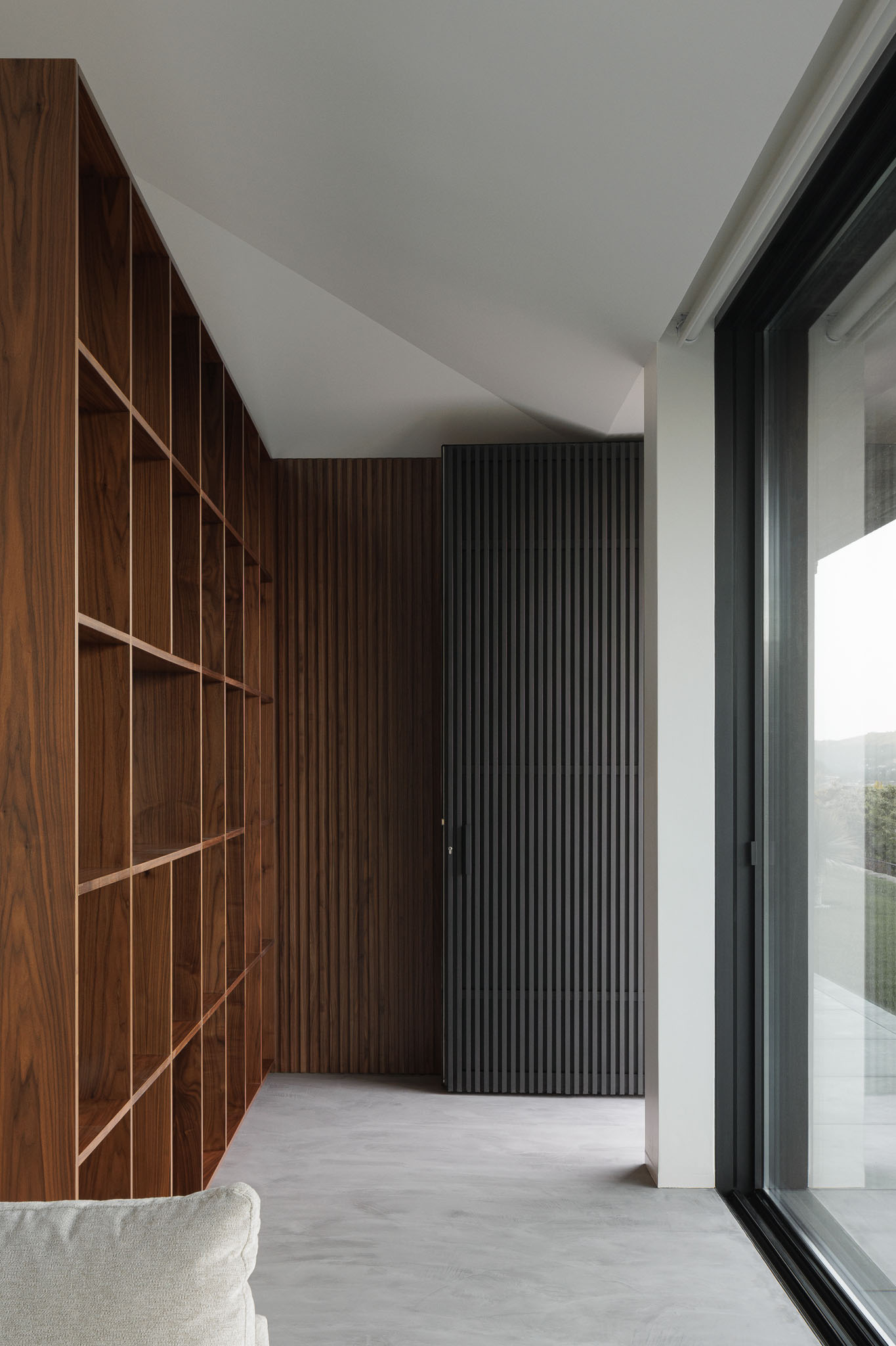 Circulação: Corredor com estante em madeira, divisória em madeira escura e janela panorâmica. — Casa Ponte arquitetura stu.dere em Amarante