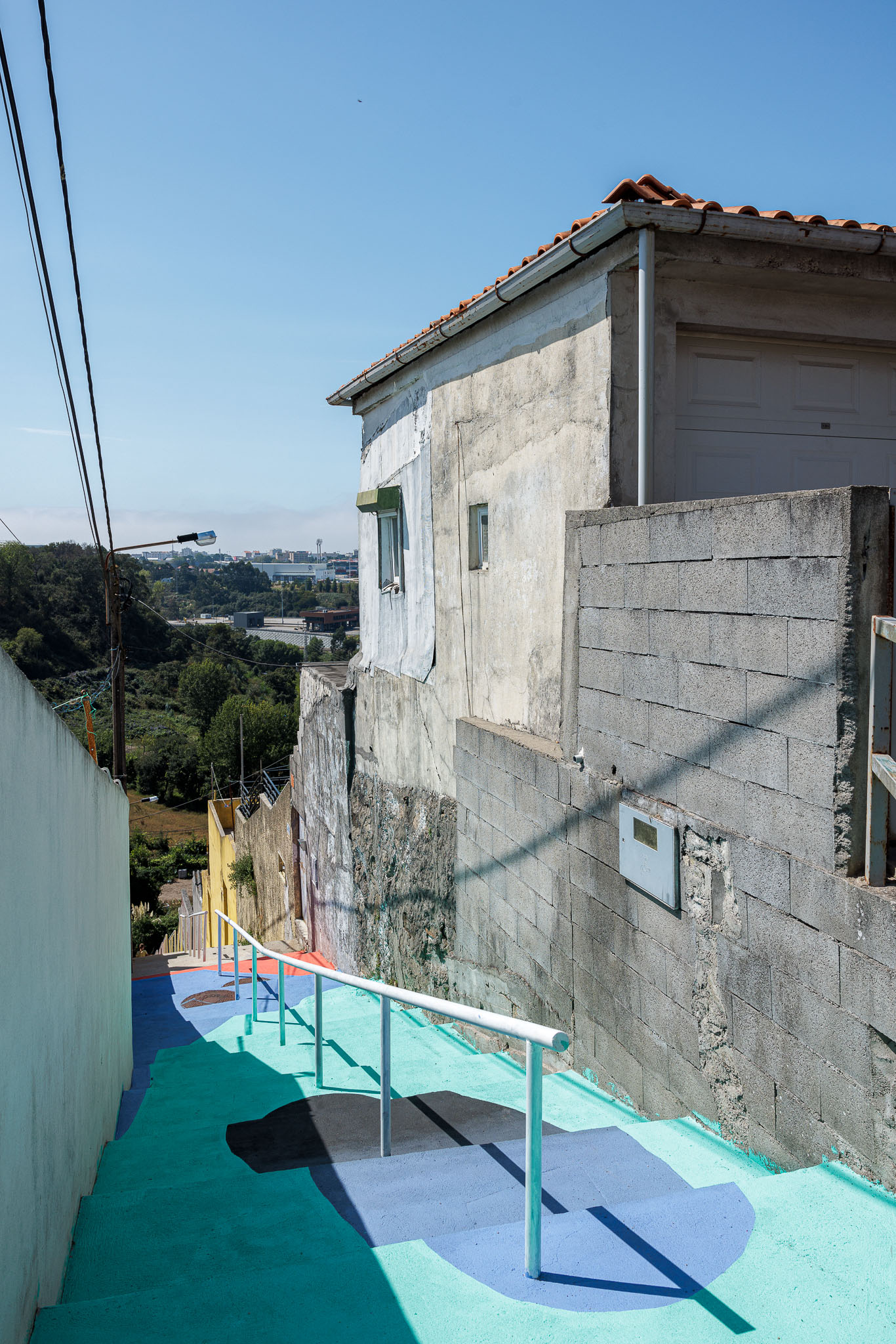 Escadaria: Degraus coloridos em betão pintado, com corrimão metálico branco, junto a edifícios. — Caminho das Escadinhas arquitetura Paulo Moreira Architectures e verkron em Matosinhos