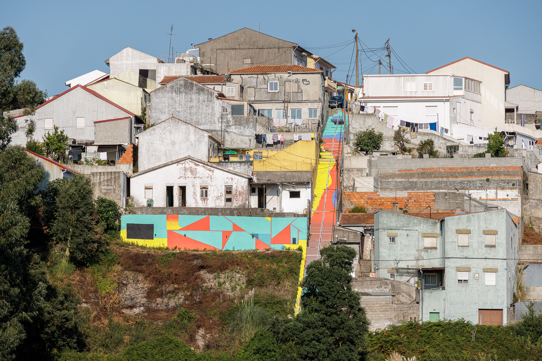 Paisagem urbana: Vista geral da escadaria colorida em betão pintado, integrada na paisagem urbana. — Caminho das Escadinhas arquitetura Paulo Moreira Architectures e verkron em Matosinhos