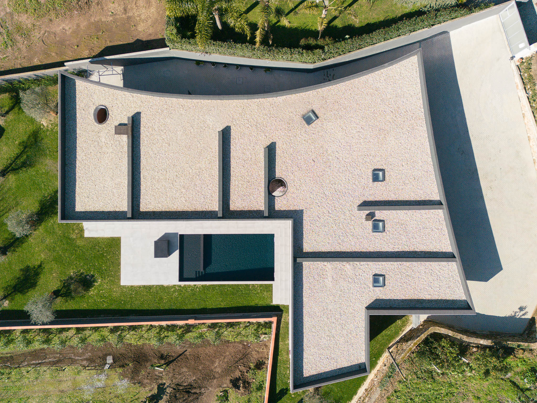 Cobertura: Vista aérea da casa com cobertura em gravilha, piscina e jardim. — TM House arquitetura Inception Architects Studio em Santo Tirso