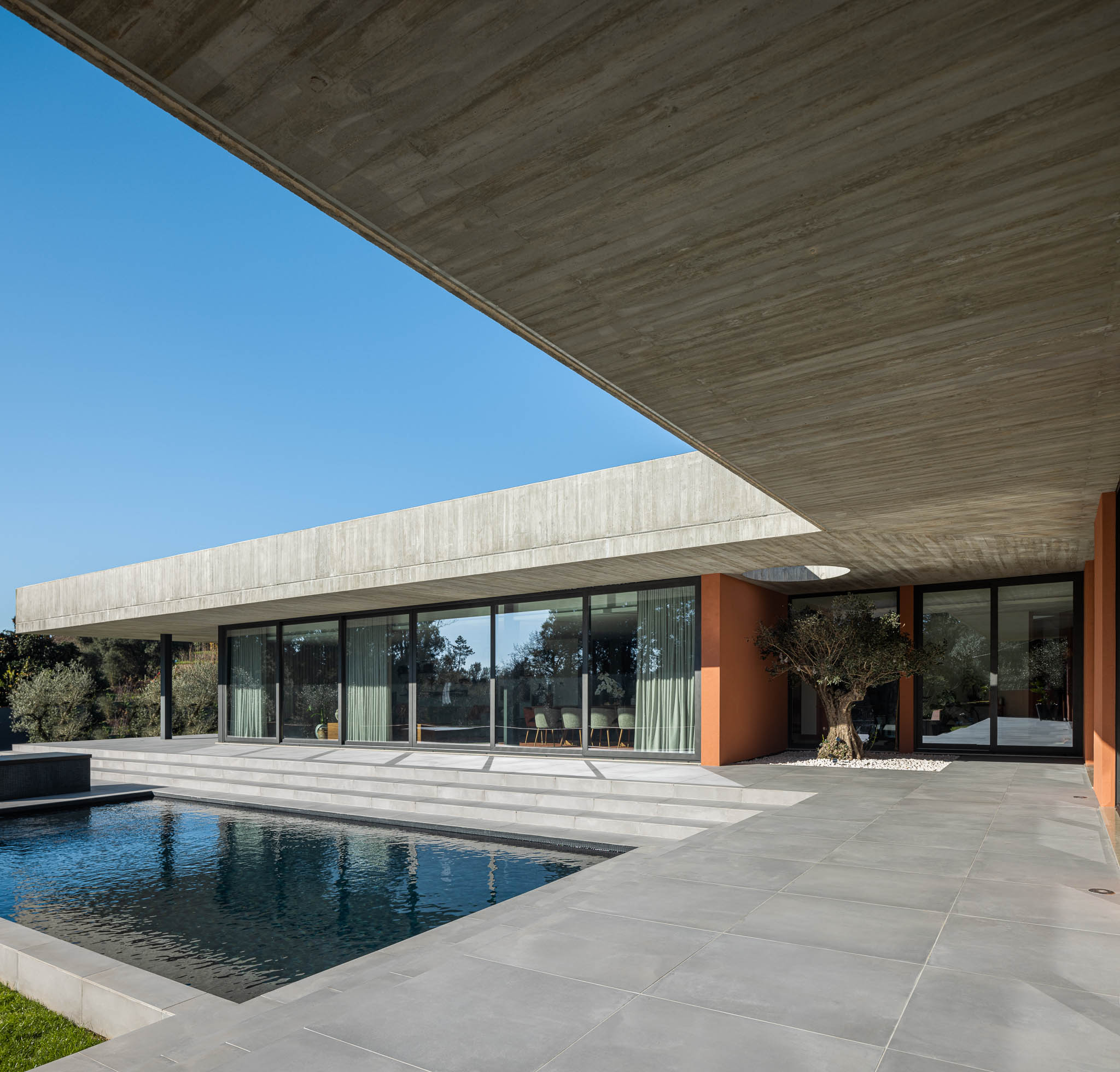 Exterior: Piscina e alpendre com laje de betão aparente, grandes janelas para a sala de jantar. — TM House arquitetura Inception Architects Studio em Santo Tirso