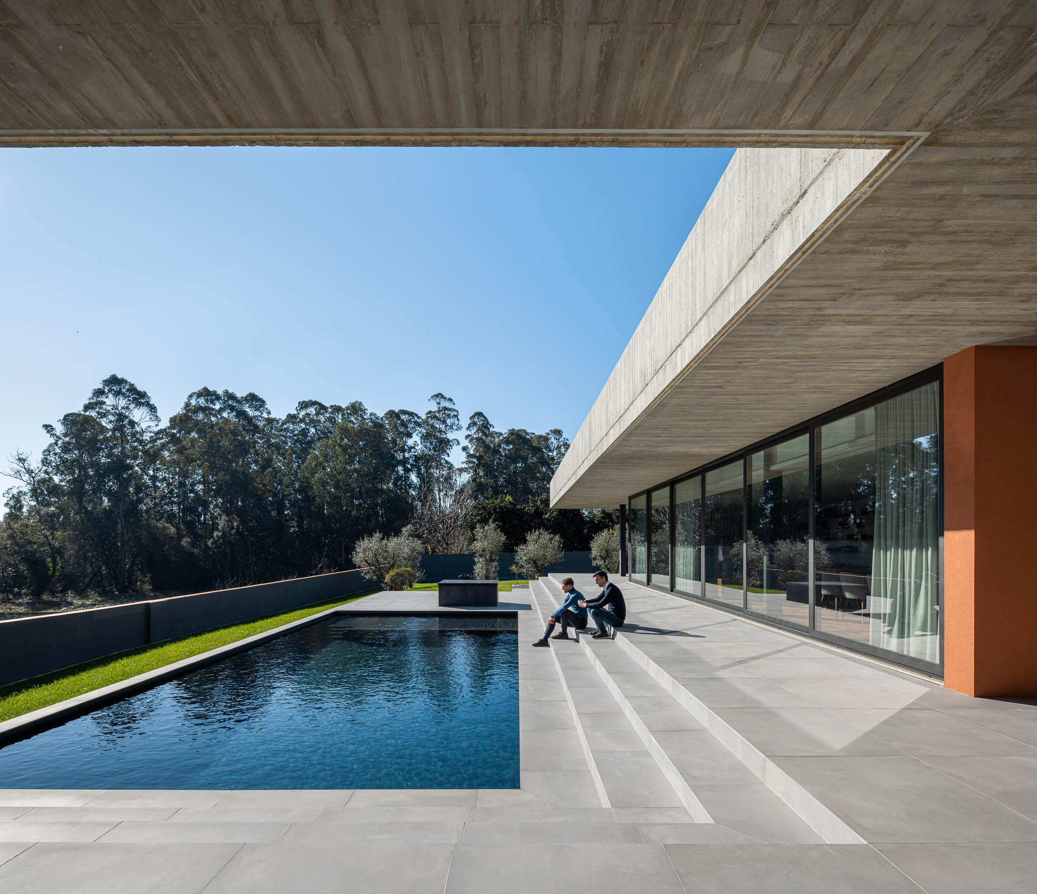 Exterior: Piscina com alpendre e laje de betão aparente, pavimento em cerâmica cinzenta. — TM House arquitetura Inception Architects Studio em Santo Tirso