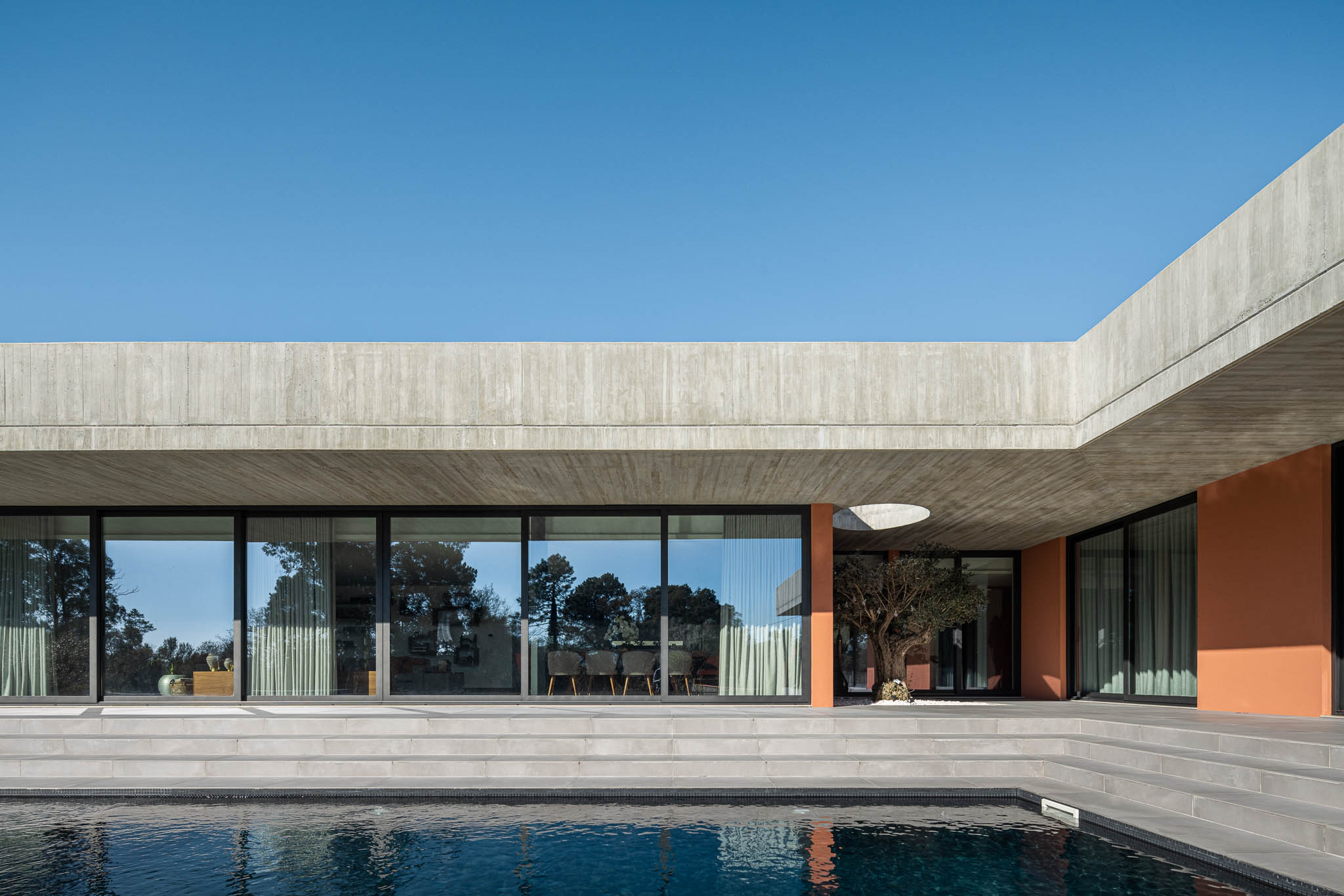 Exterior: Piscina com alpendre e laje de betão aparente, grandes janelas para a sala de jantar. — TM House arquitetura Inception Architects Studio em Santo Tirso