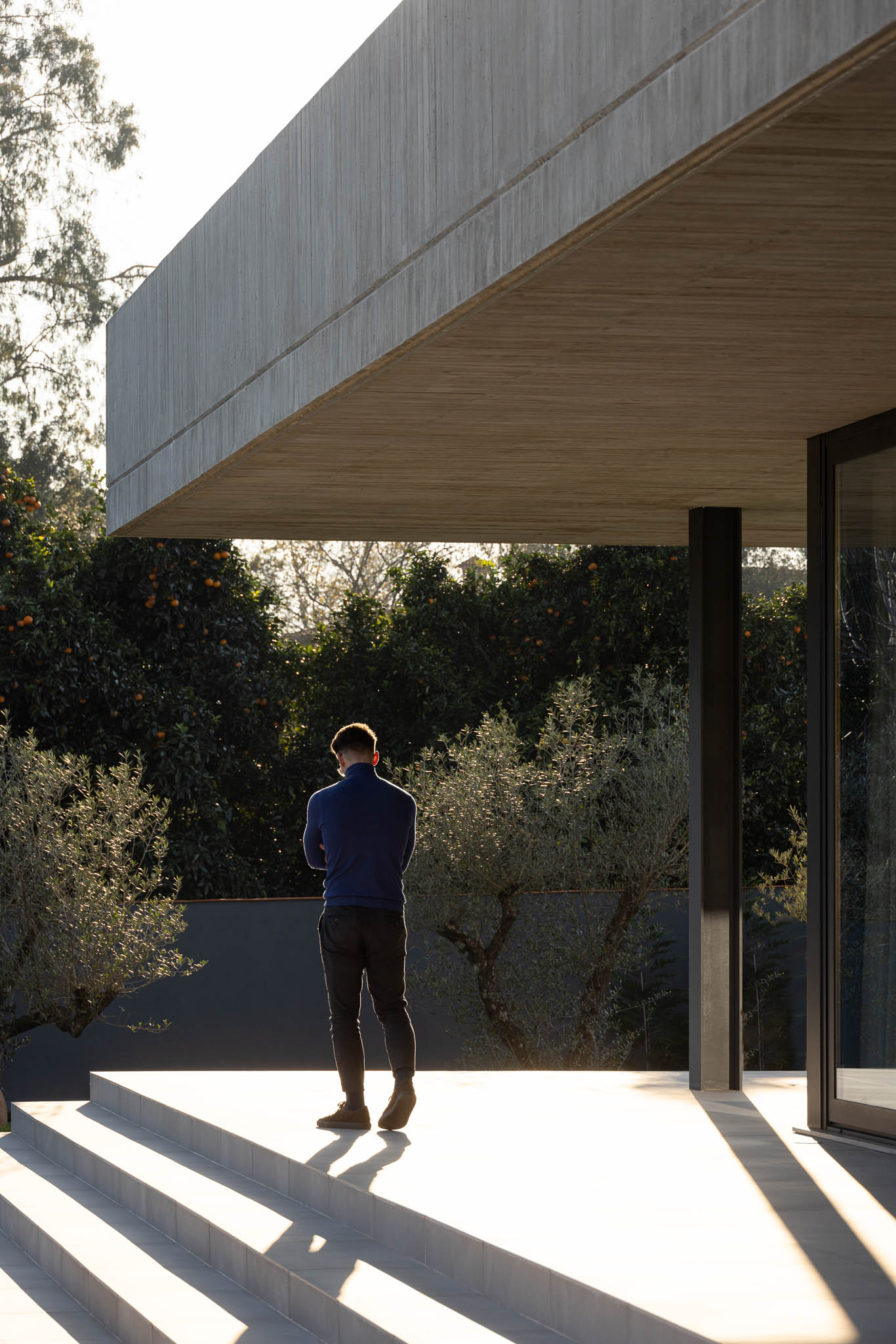 Corredor: Portas em madeira com design curvo, pavimento em cerâmica cinzenta. — TM House arquitetura Inception Architects Studio em Santo Tirso