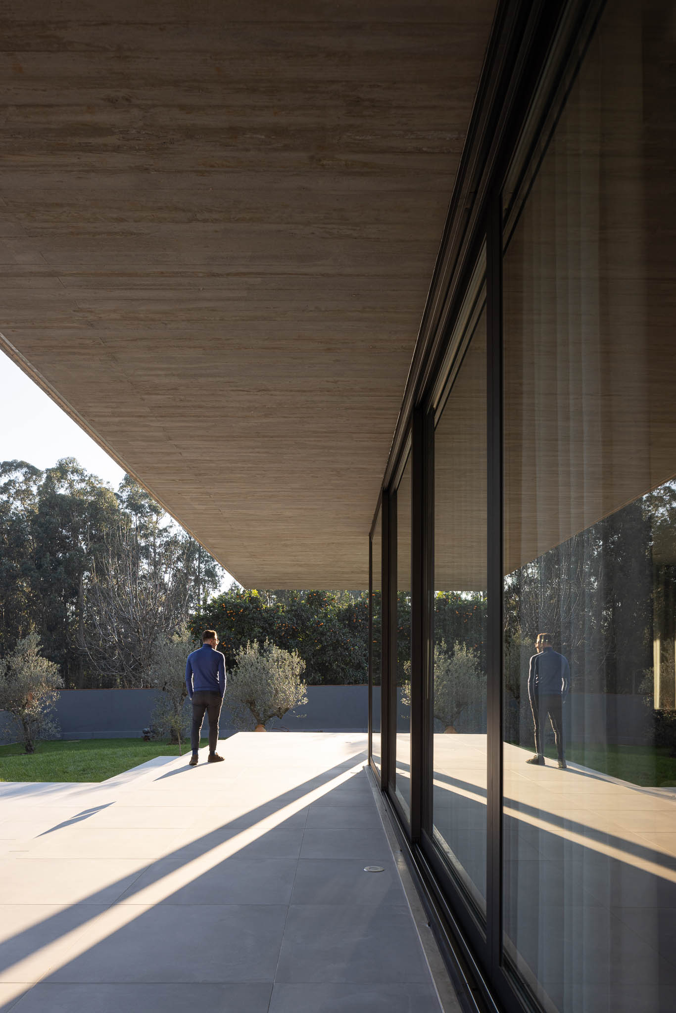 Exterior: Alpendre com laje de betão aparente, pavimento em cerâmica cinzenta. — TM House arquitetura Inception Architects Studio em Santo Tirso
