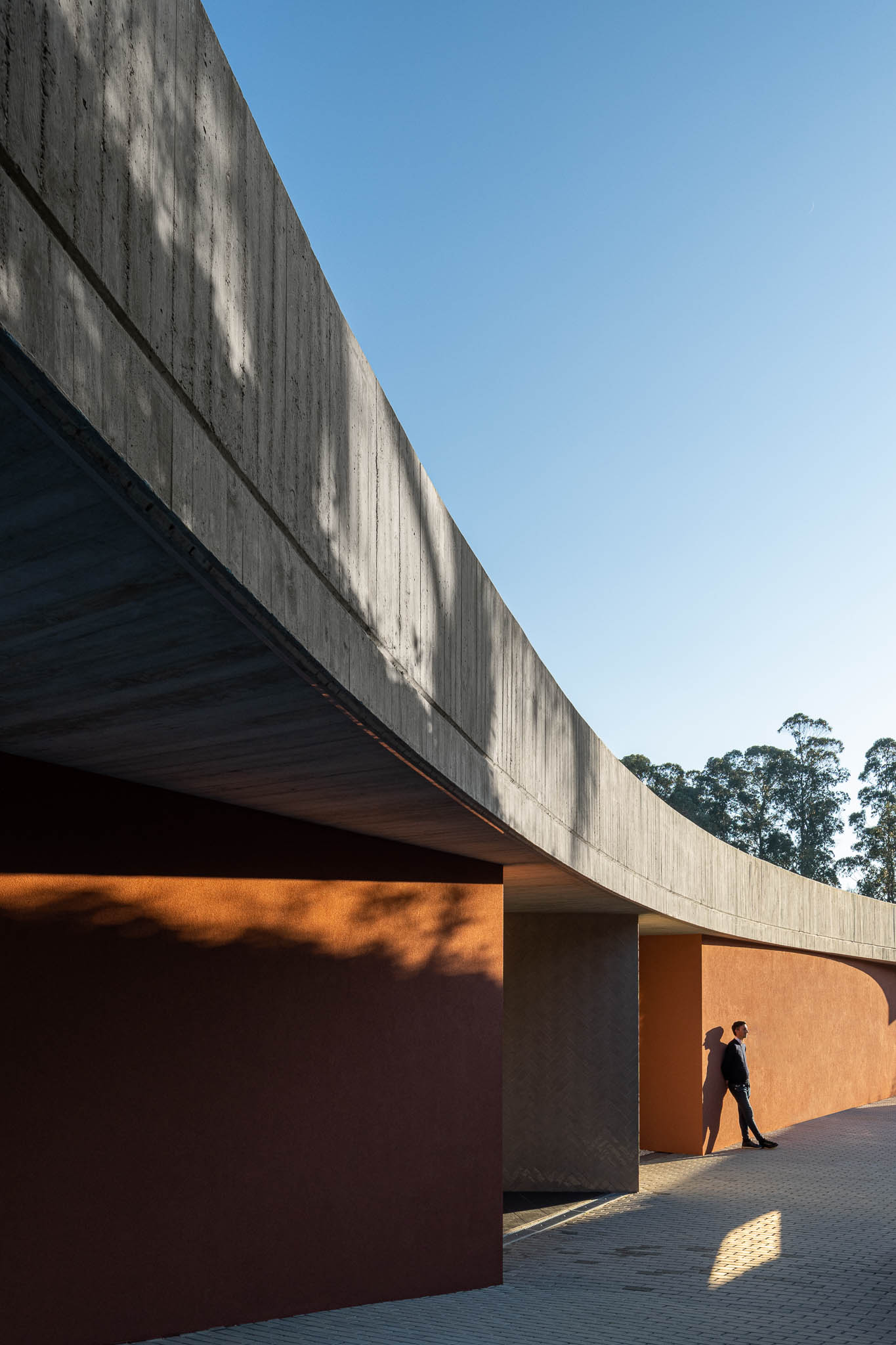 Exterior: Alpendre com laje de betão aparente, grandes janelas, pavimento em cerâmica cinzenta. — TM House arquitetura Inception Architects Studio em Santo Tirso