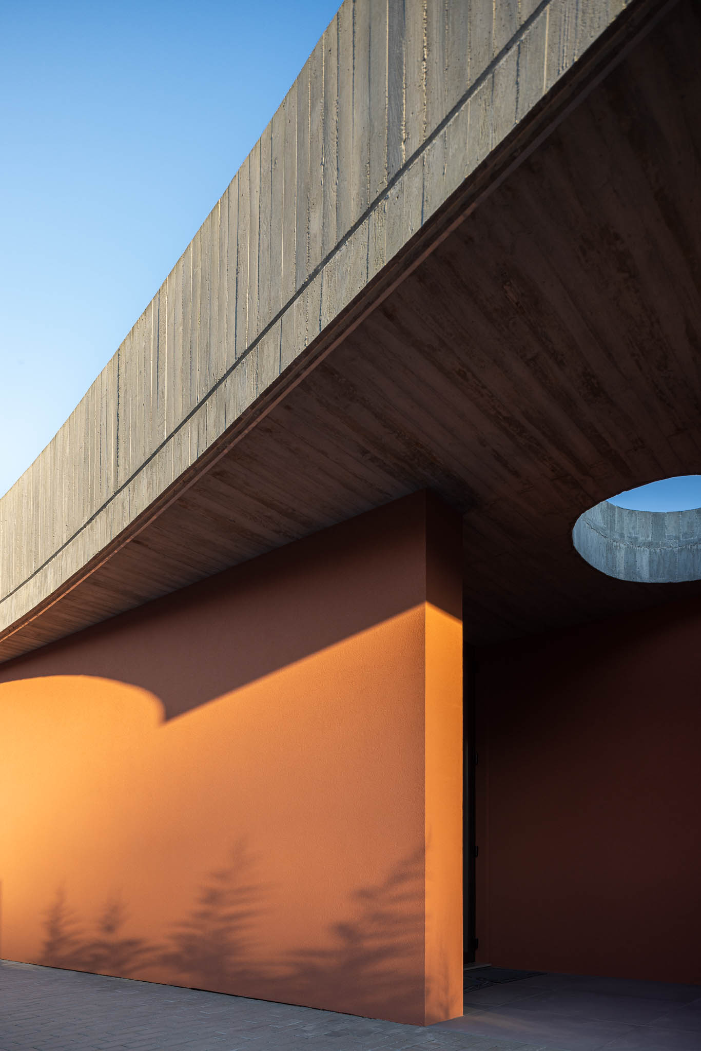 Exterior: Laje de betão aparente com orifício circular. Paredes cor de tijolo. — TM House arquitetura Inception Architects Studio em Santo Tirso