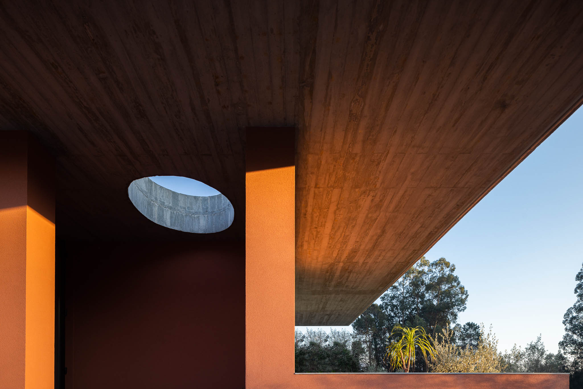 Exterior: Laje de betão aparente com orifício circular. Paredes cor de tijolo. — TM House arquitetura Inception Architects Studio em Santo Tirso