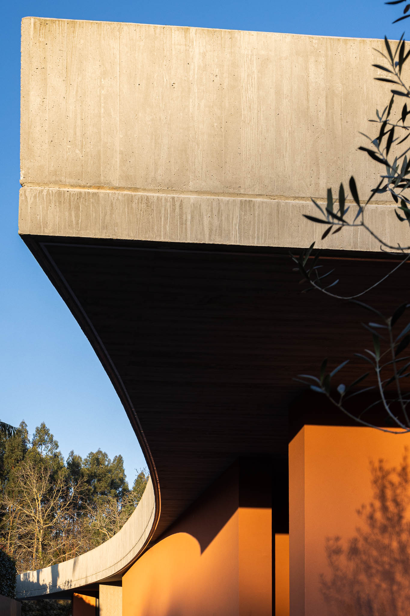 Exterior: Laje de betão aparente com forma curva e paredes cor de tijolo. — TM House arquitetura Inception Architects Studio em Santo Tirso