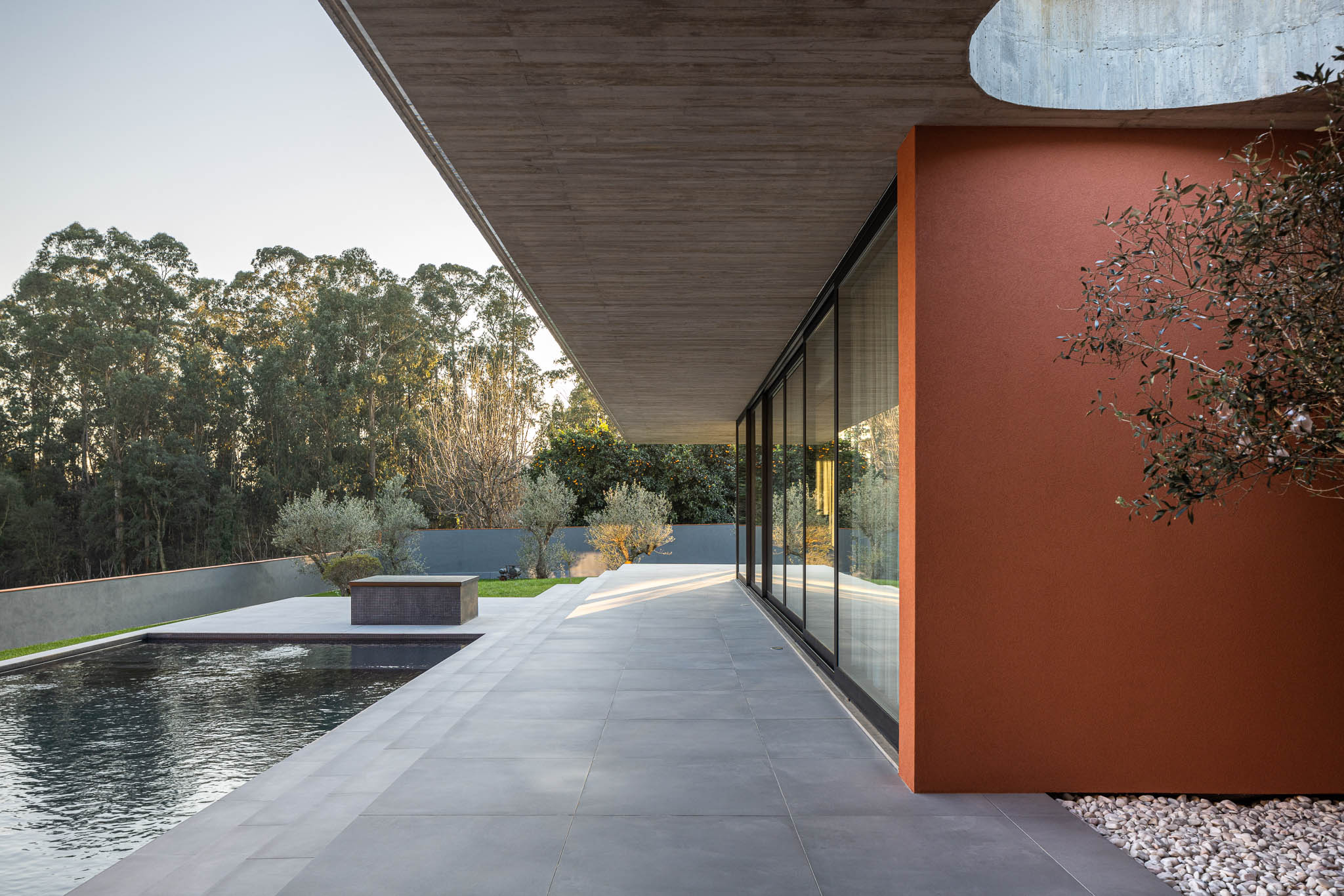 Exterior: Piscina e alpendre com laje de betão aparente, pavimento em cerâmica cinzenta. — TM House arquitetura Inception Architects Studio em Santo Tirso