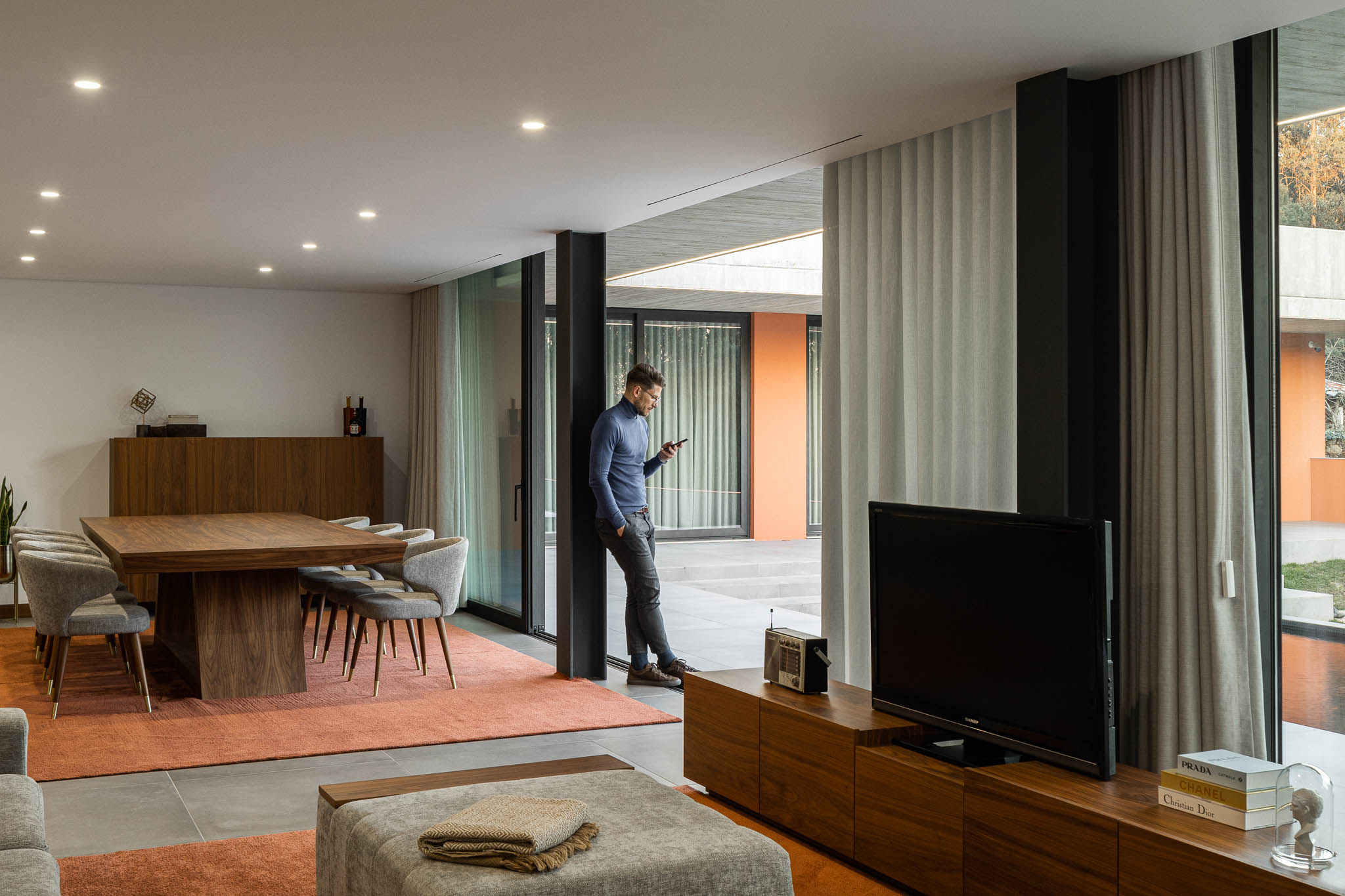Sala de estar: Sala de estar e jantar com alcatifa cor de laranja e mobiliário em madeira. — TM House arquitetura Inception Architects Studio em Santo Tirso