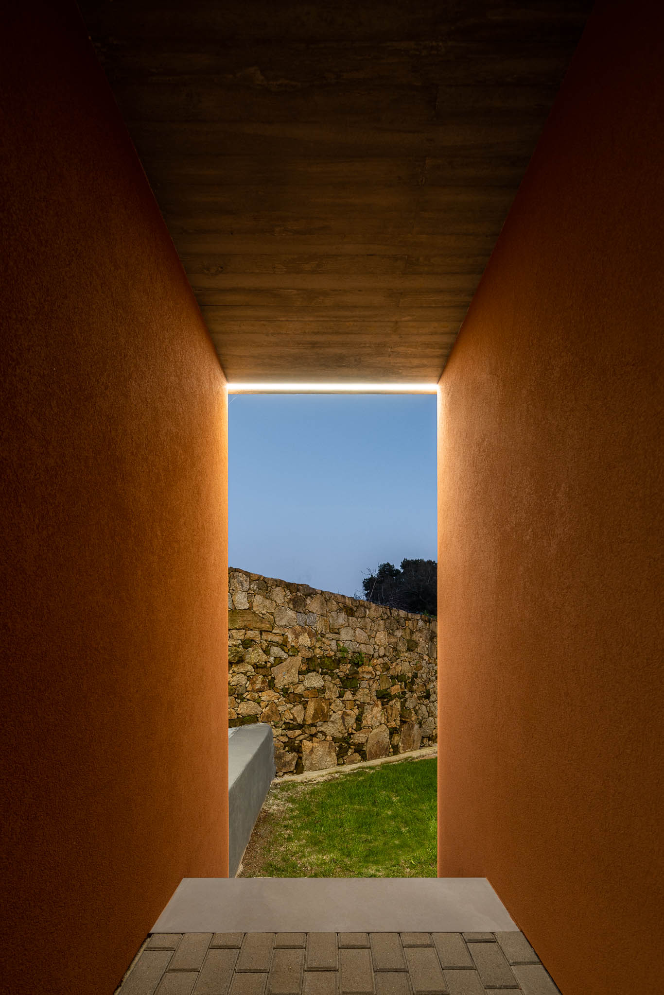 Exterior: Corredor exterior com paredes cor de tijolo e laje de betão aparente. — TM House arquitetura Inception Architects Studio em Santo Tirso