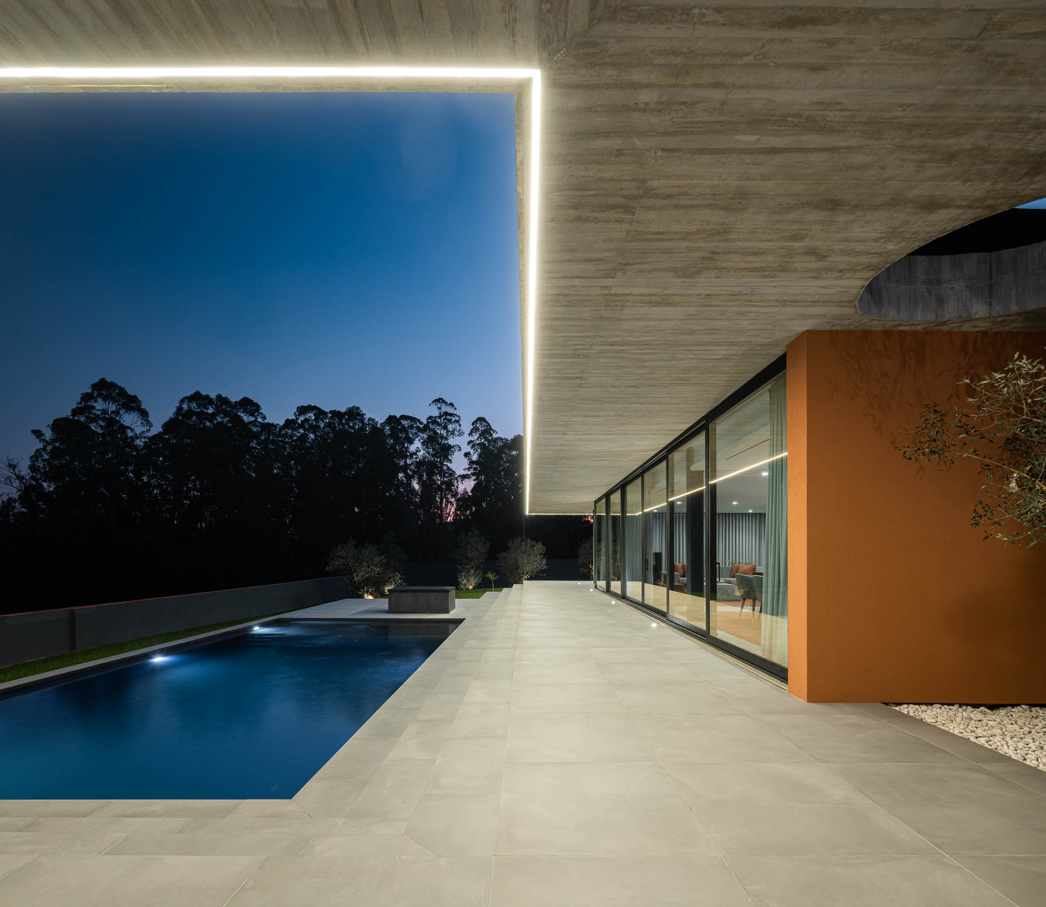 Exterior: Vista noturna da casa com piscina, laje de betão aparente com orifício circular. — TM House arquitetura Inception Architects Studio em Santo Tirso