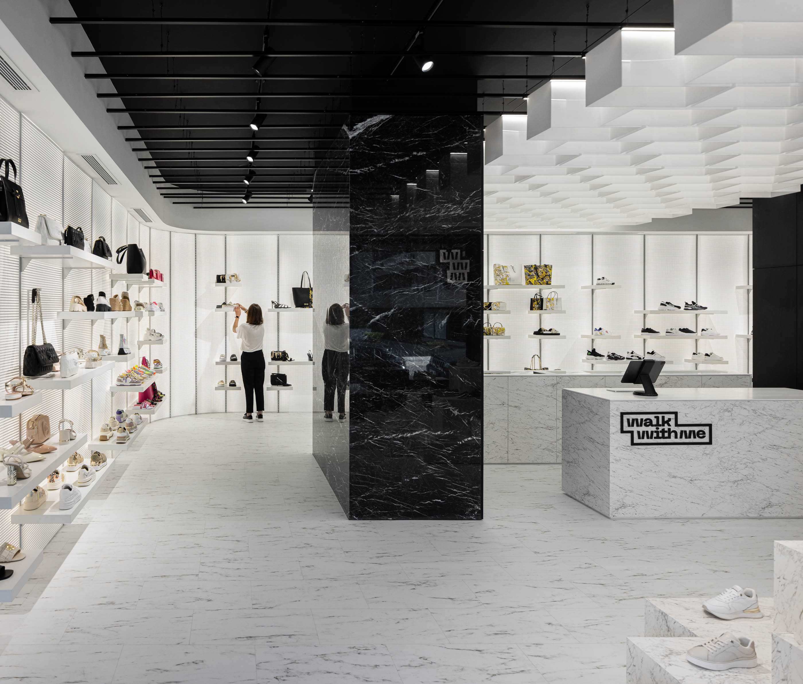 Loja: Vista geral do interior com prateleiras iluminadas, balcão em mármore e pavimento em mármore branco. — Walk With Me Store arquitetura REM'A Arquitectos em Porto