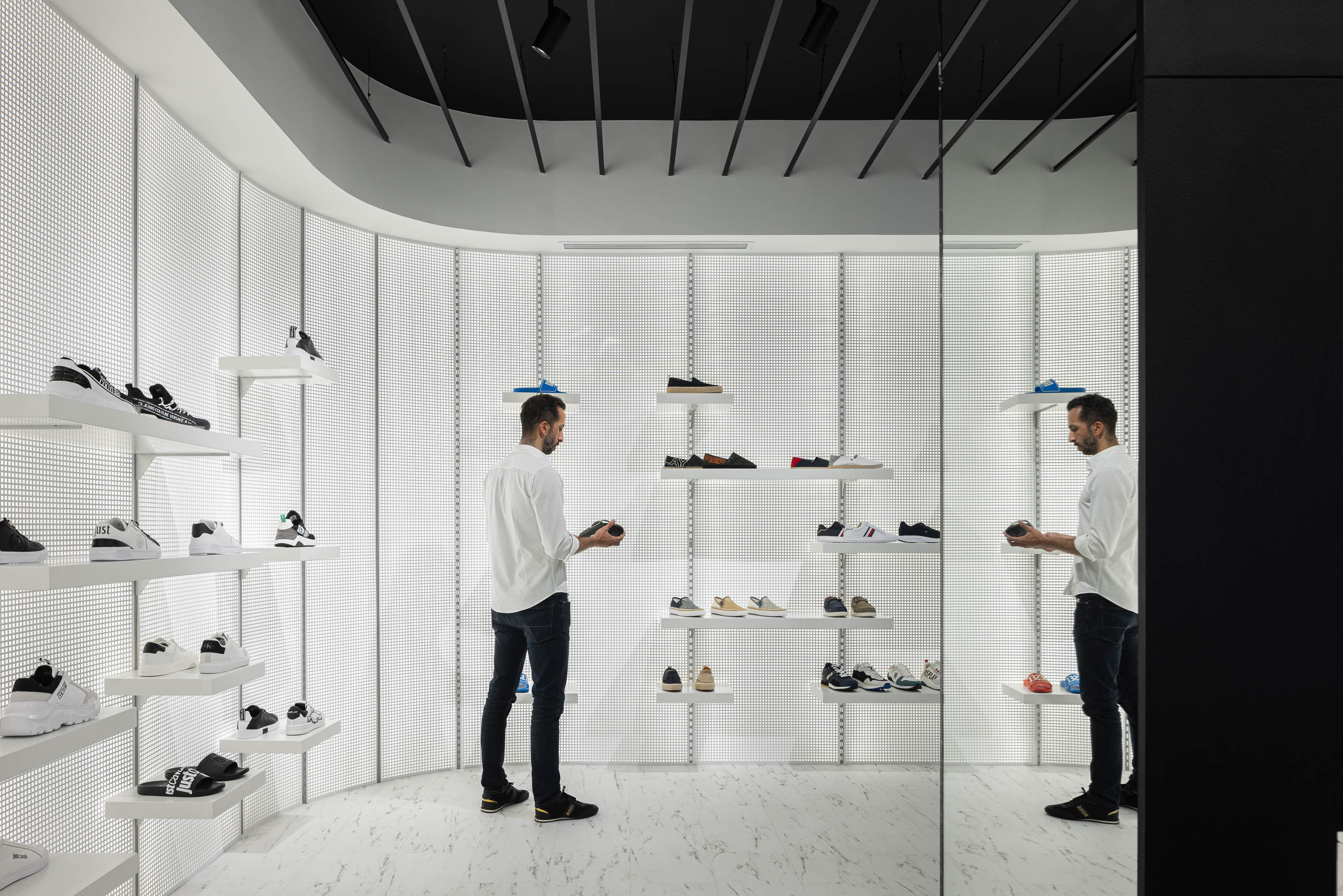 Loja: Prateleiras com calçado e espelho, teto preto com candeeiros e pavimento em mármore branco. — Walk With Me Store arquitetura REM'A Arquitectos em Porto