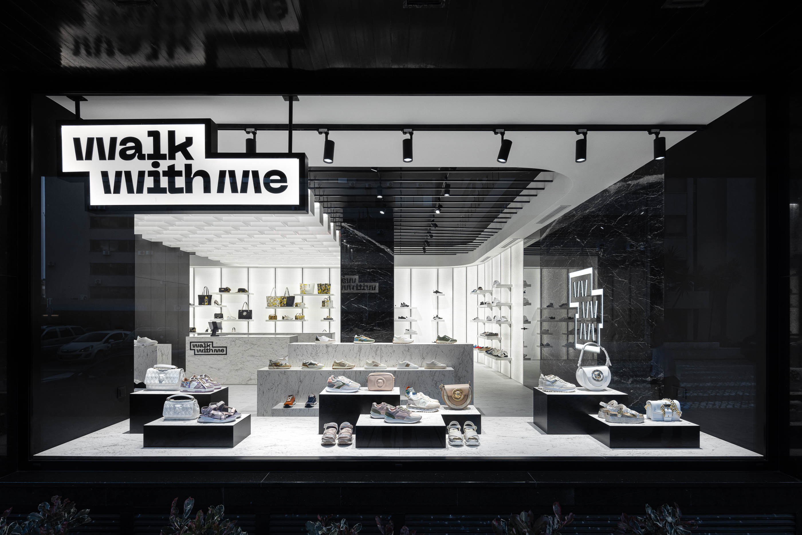Fachada: Vista exterior da loja com montra, logótipo iluminado e interior visível. — Walk With Me Store arquitetura REM'A Arquitectos em Porto