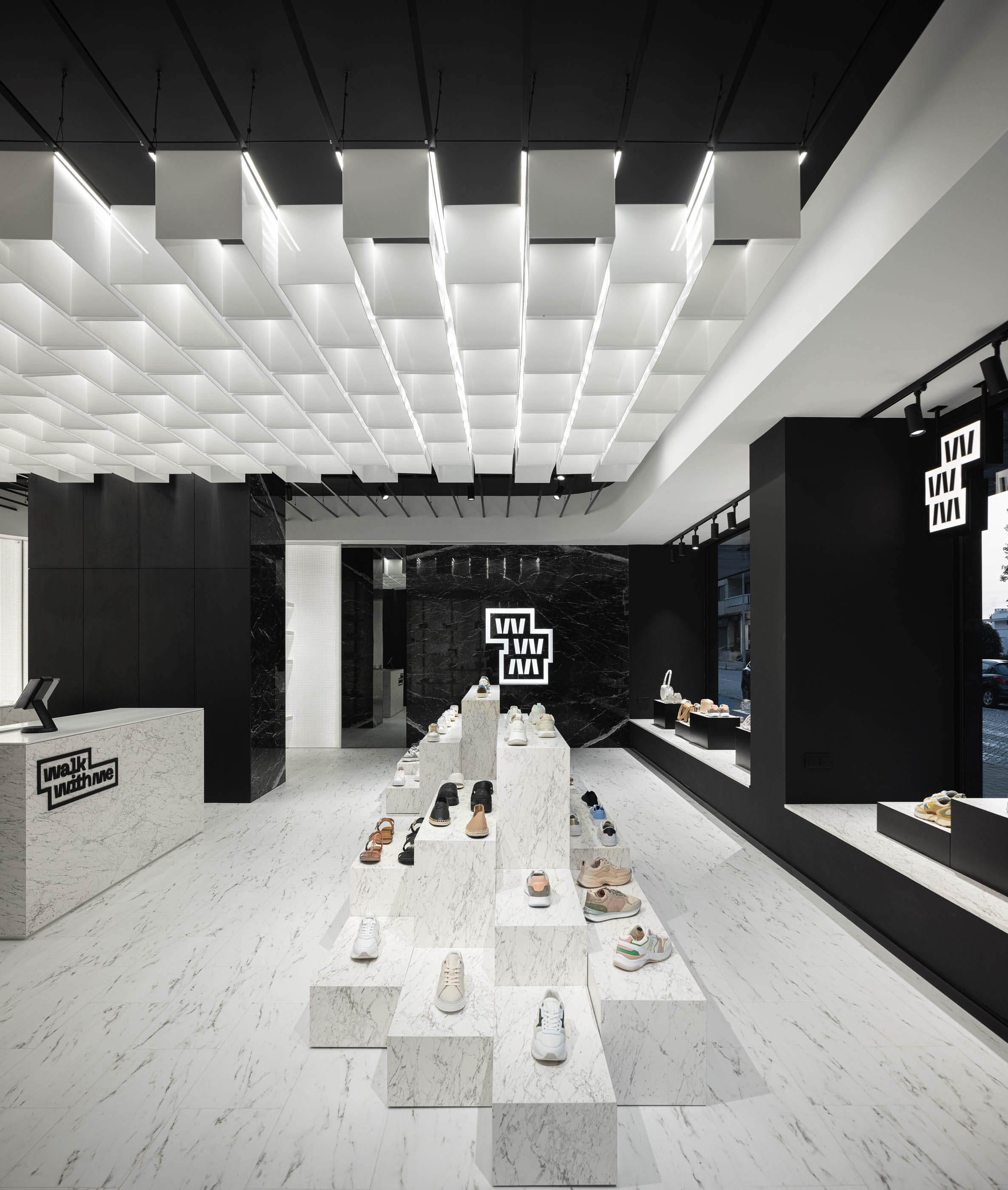 Loja: Vista geral do interior com balcão, expositores em mármore e teto com elementos geométricos. — Walk With Me Store arquitetura REM'A Arquitectos em Porto