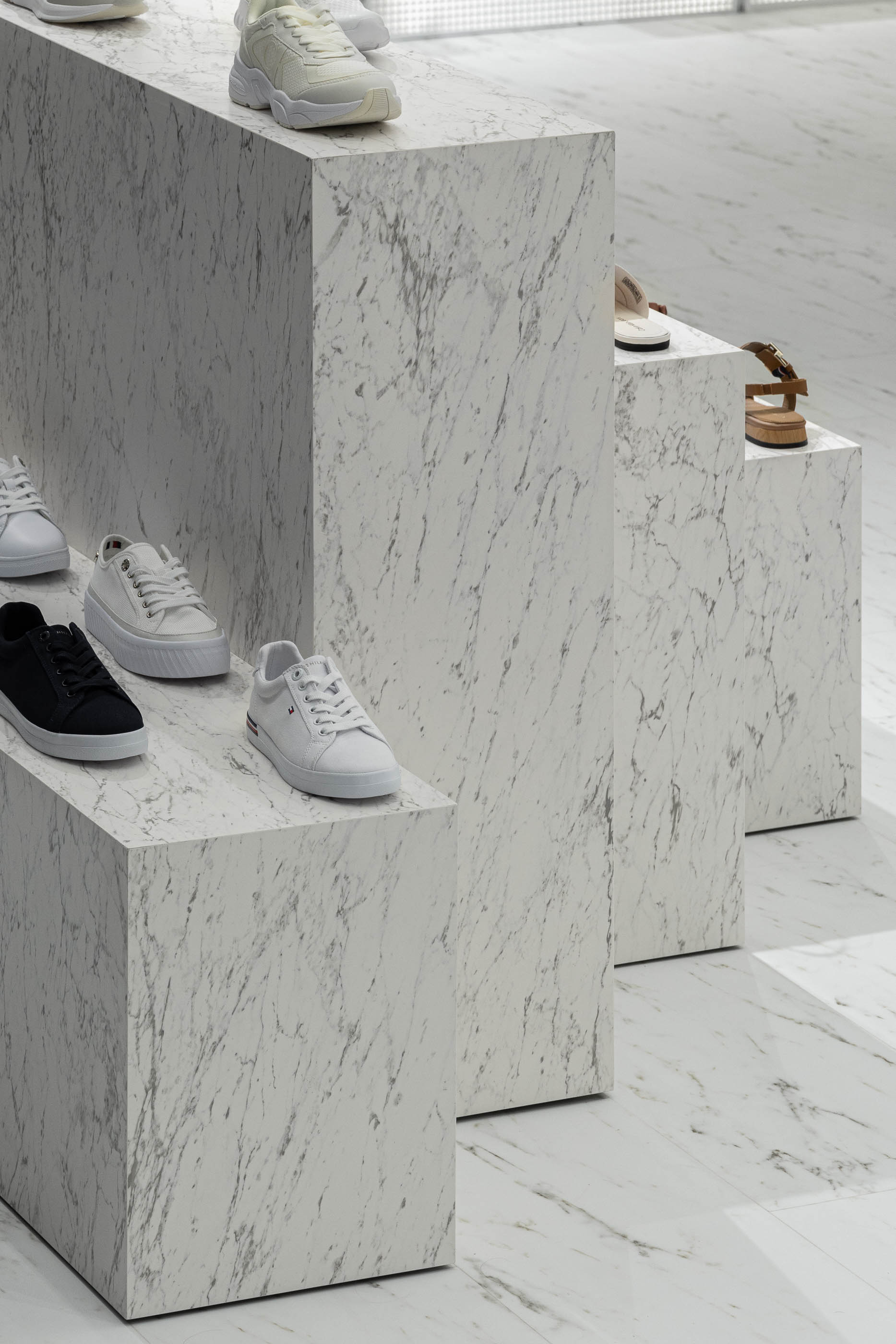 Loja: Detalhe de expositores em mármore branco com calçado. — Walk With Me Store arquitetura REM'A Arquitectos em Porto