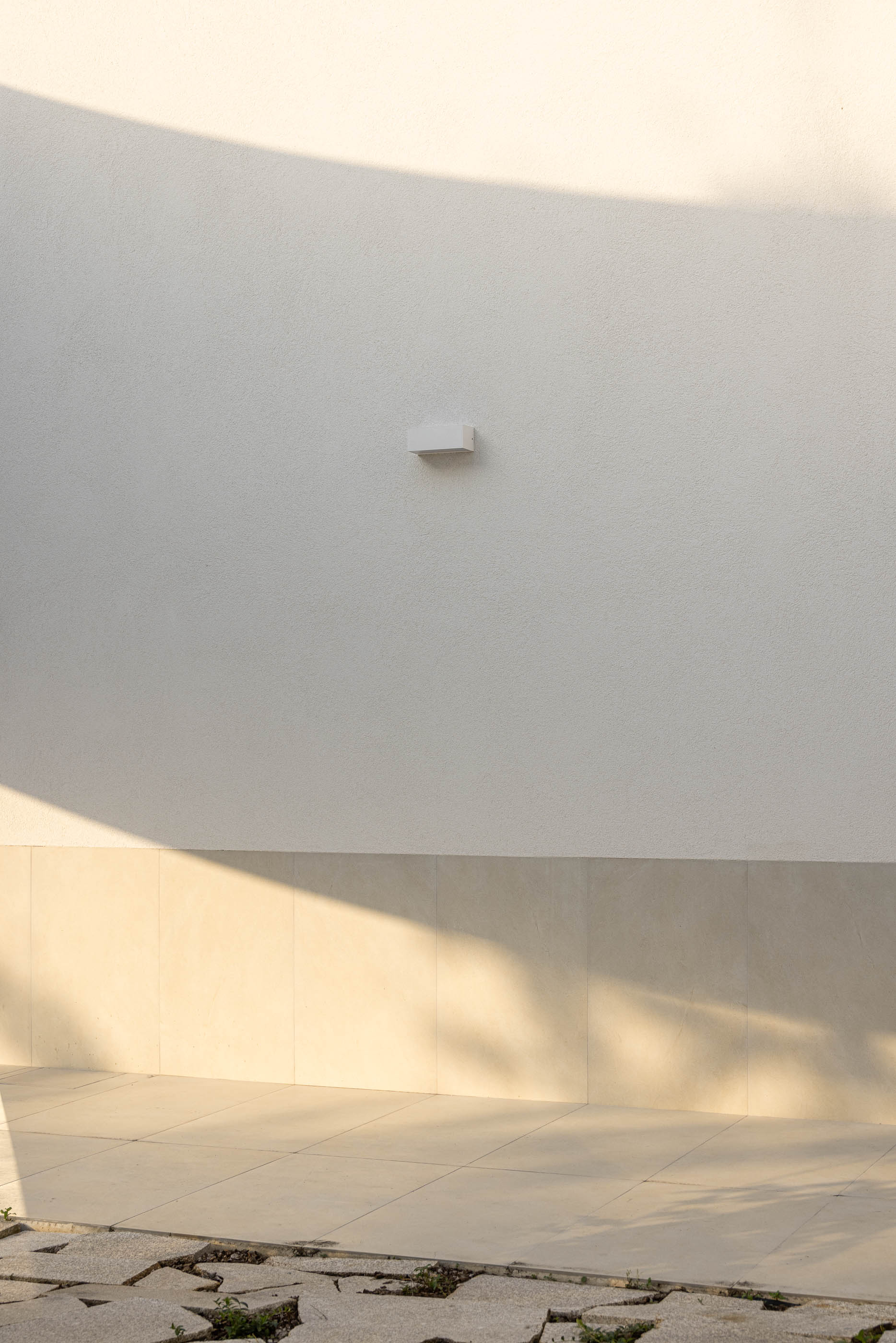 Exterior: Detalhe da fachada curva com porta de vidro e estacionamento. — Farmácia da Devesa arquitetura Tsou Arquitectos em Vila Nova de Famalicão