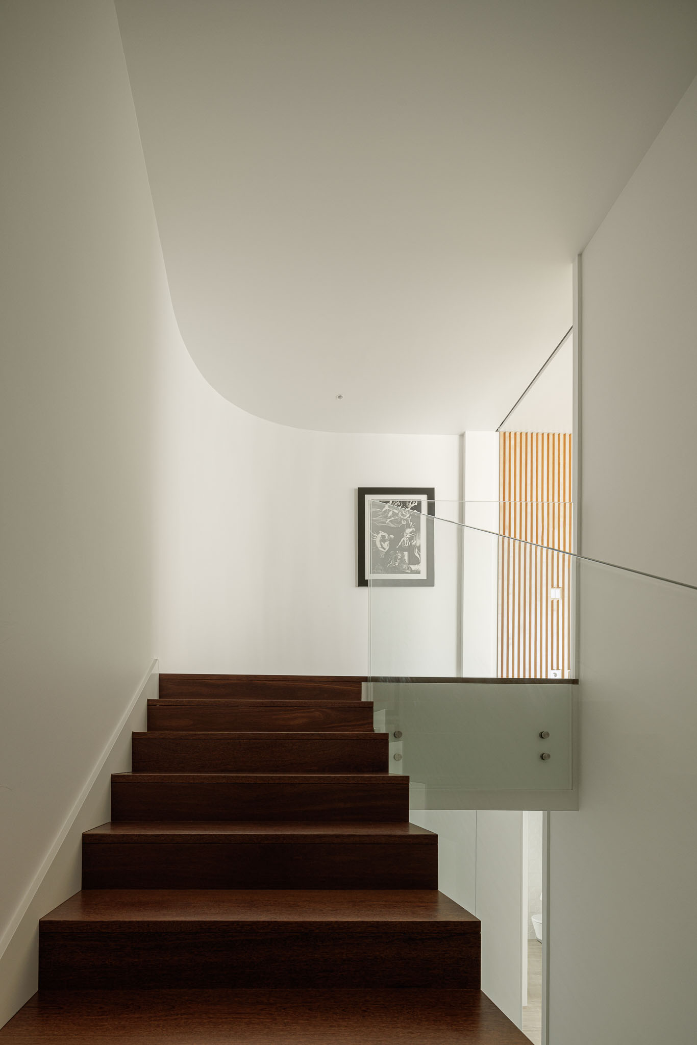 Escada: Degraus em madeira escura contrastam com paredes brancas e guarda em vidro, estilo minimalista. — Moradia JD2 arquitetura Rui Rosmaninho Arquiteto em Ílhavo