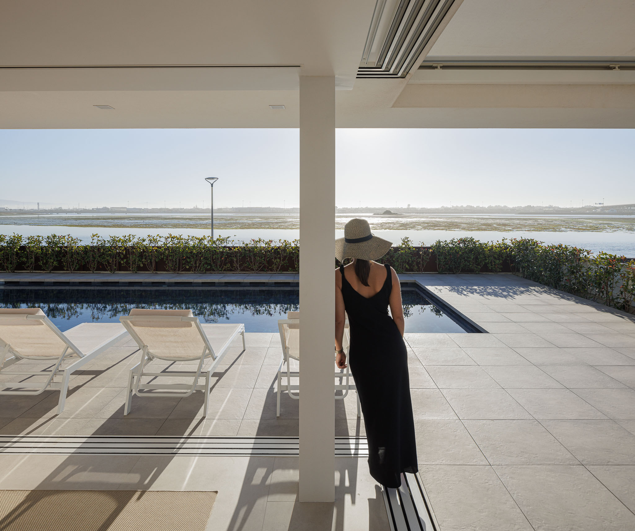 Cozinha: Ilha branca, armários brancos, zona de refeições e sala de estar integradas, com vista para a ria. — Moradia JD2 arquitetura Rui Rosmaninho Arquiteto em Ílhavo