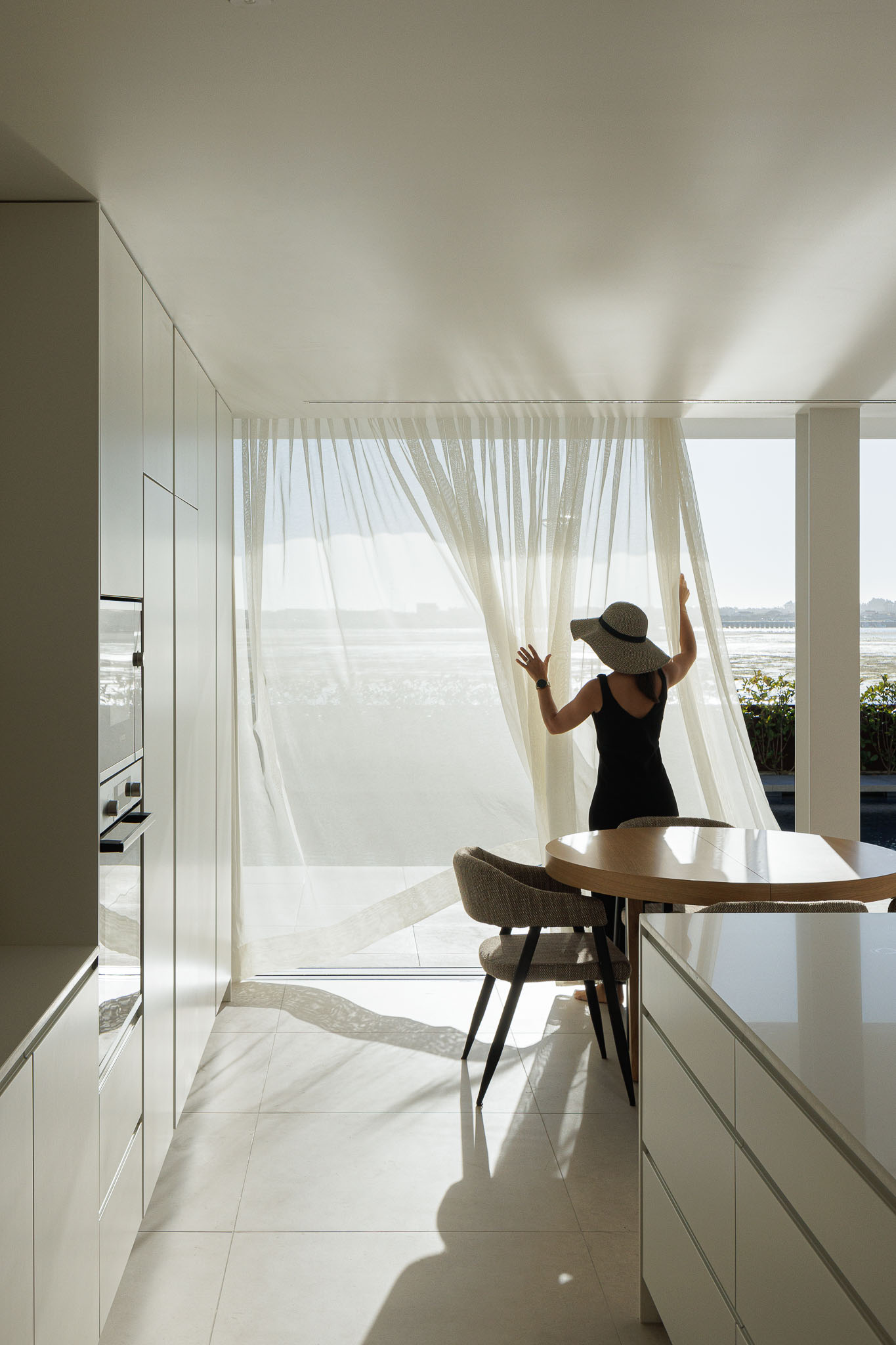 Exterior: Fachada branca com elementos curvos, varandas com guarda em vidro e vista para a ria. — Moradia JD2 arquitetura Rui Rosmaninho Arquiteto em Ílhavo