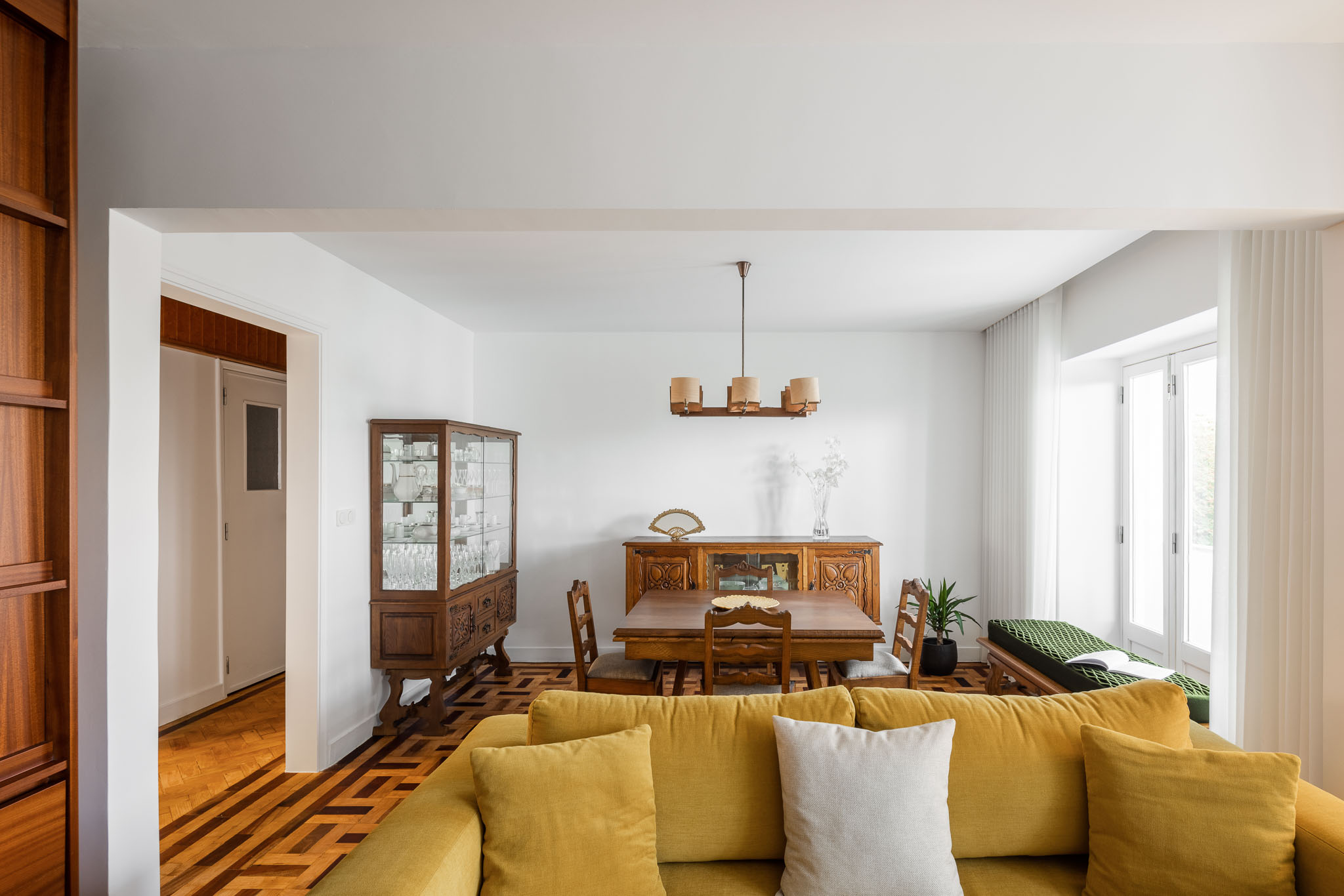 Sala de estar/jantar: Sofá amarelo, mesa de jantar em madeira e aparador clássico. Pavimento em madeira com padrão geométrico. — Apartamento em Gouveia arquitetura M2Senos Arquitectos em Gouveia