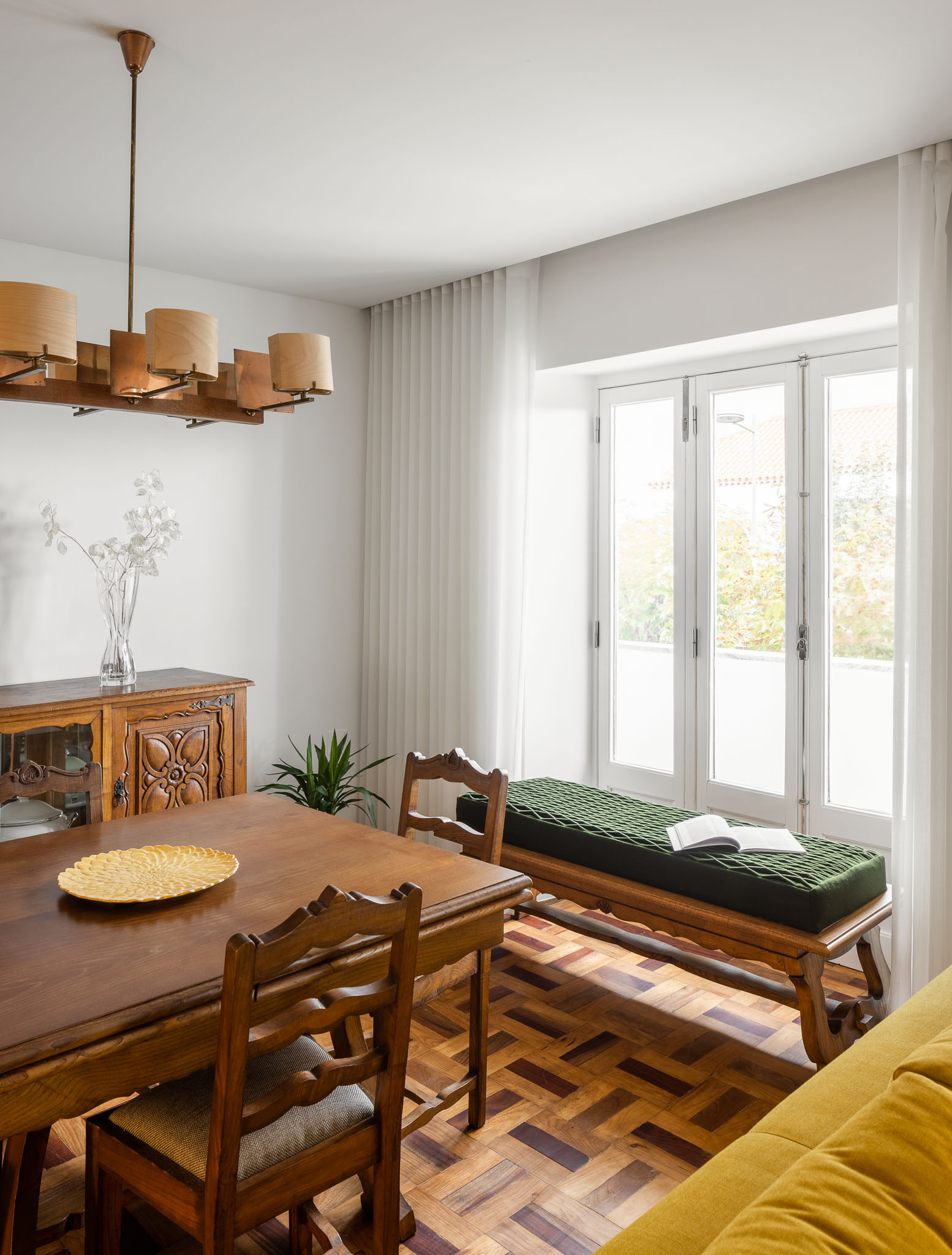 Sala de jantar: Detalhe da mesa de jantar em madeira, aparador clássico e banco junto à janela. Pavimento em madeira. — Apartamento em Gouveia arquitetura M2Senos Arquitectos em Gouveia