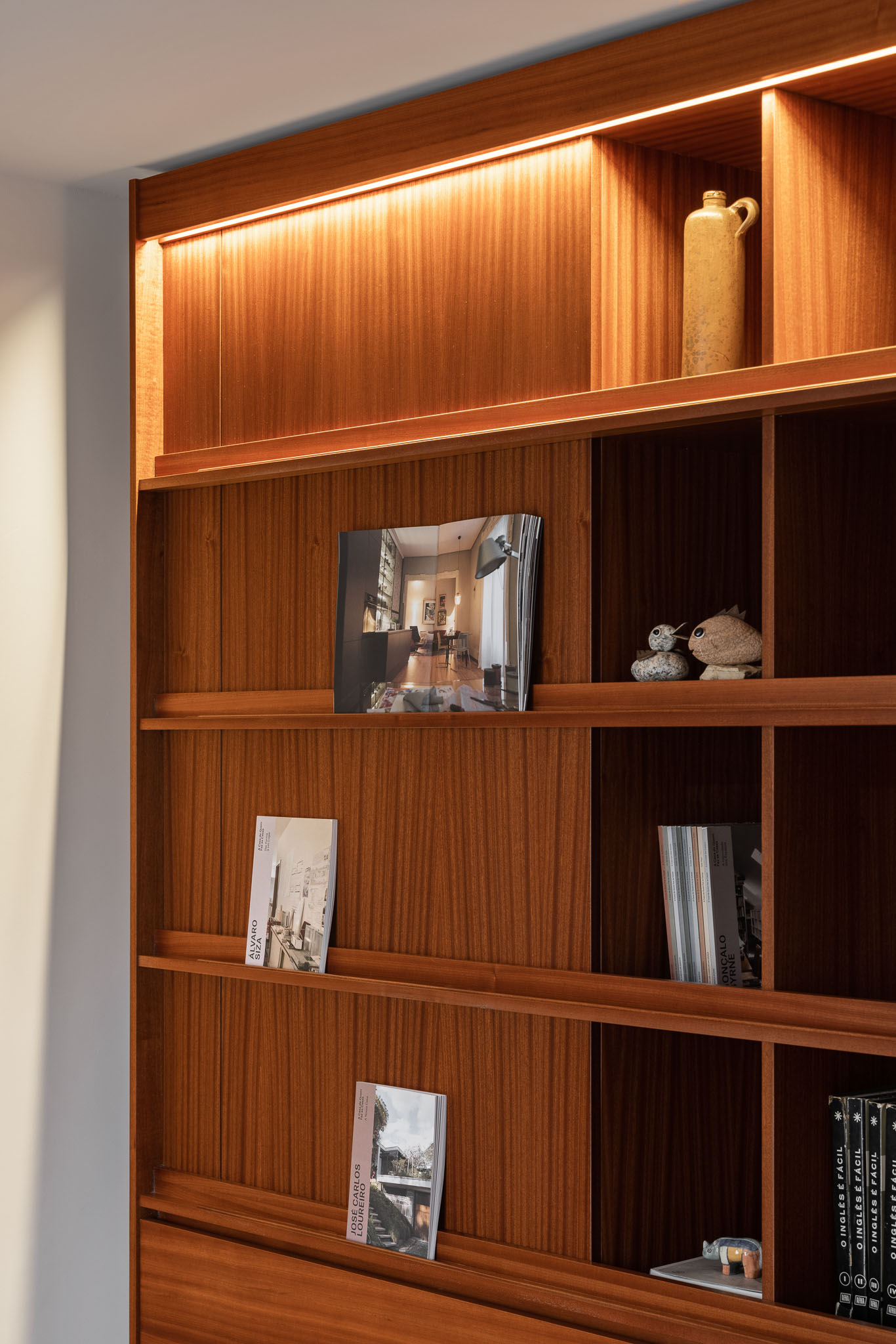 Estante: Detalhe da estante em madeira com iluminação embutida e objetos decorativos. — Apartamento em Gouveia arquitetura M2Senos Arquitectos em Gouveia