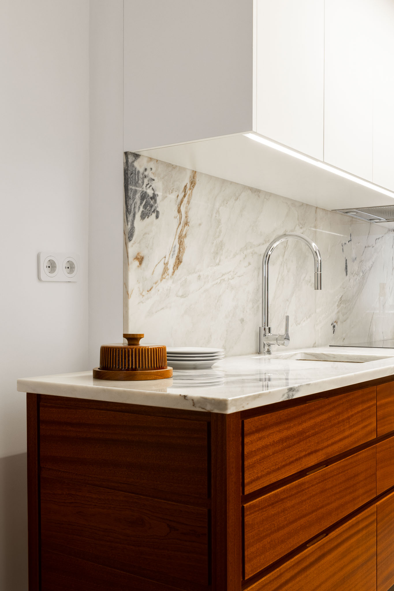 Cozinha: Detalhe da bancada em mármore com lava-loiça e armários em madeira. Revestimento em mármore na parede. — Apartamento em Gouveia arquitetura M2Senos Arquitectos em Gouveia