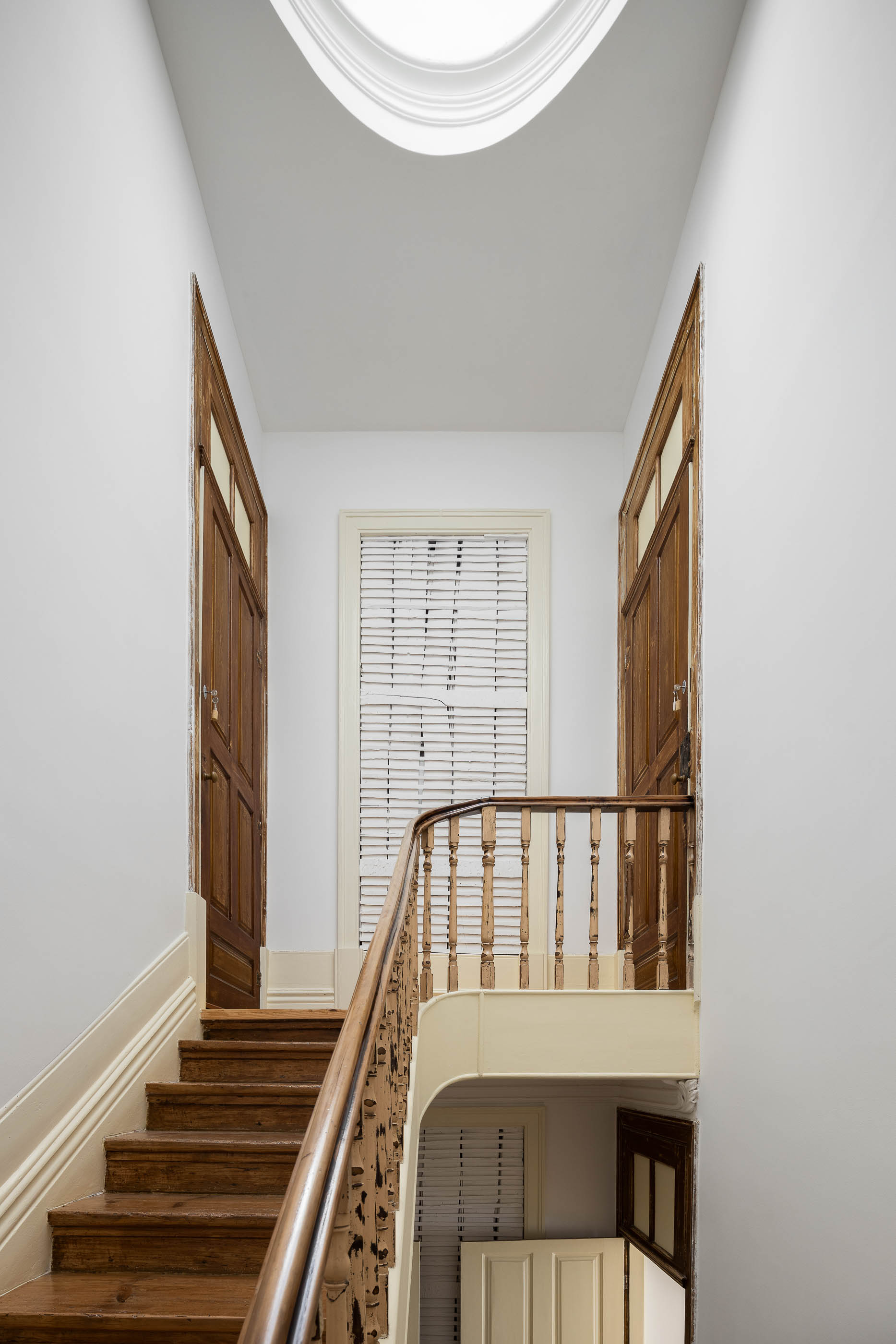 Escadaria com corrimão em madeira, pavimento em madeira e claraboia no teto. — Casa Cedofeita arquitetura Paulo Moreira Architectures em Porto