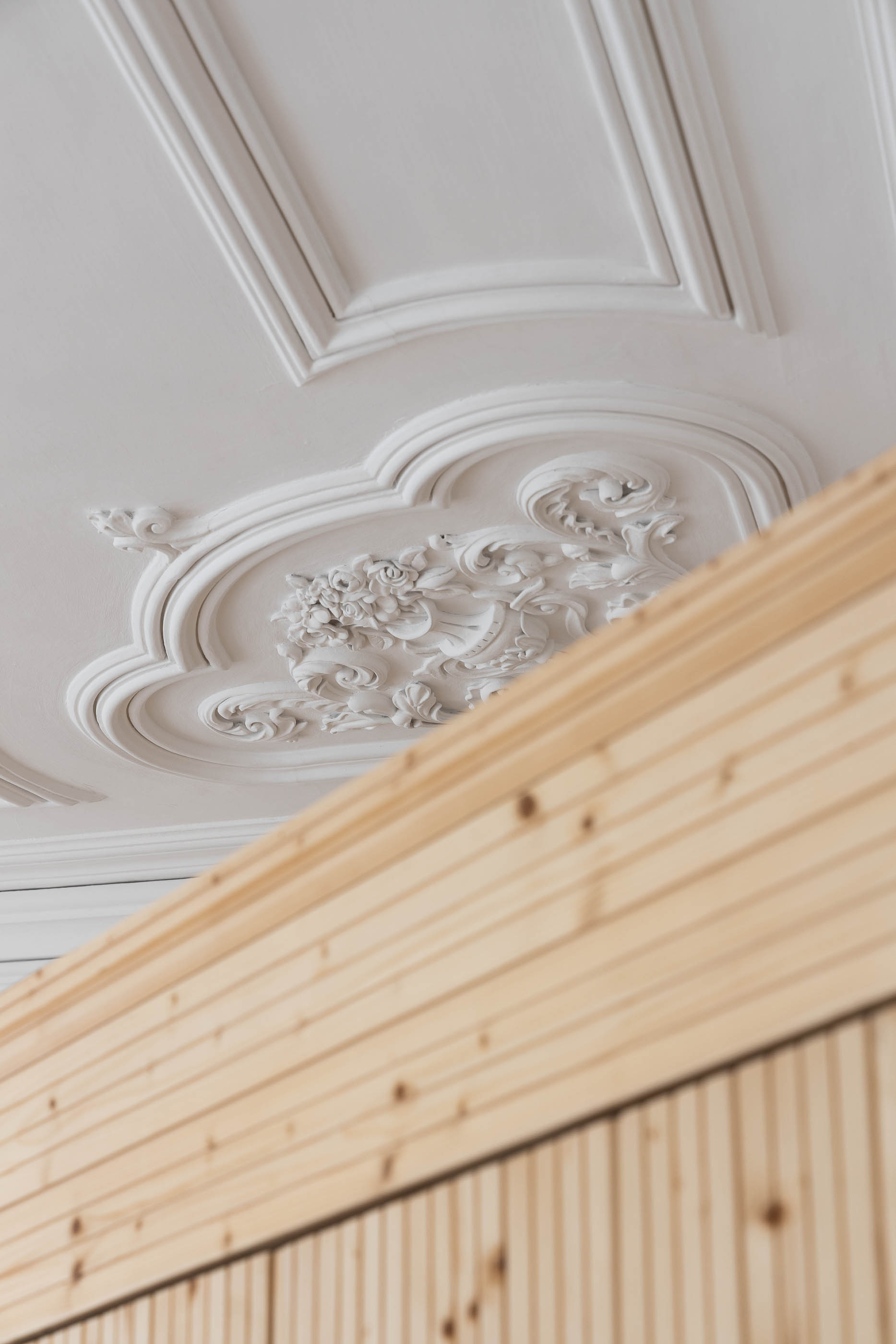 Detalhe do teto com molduras decorativas e roupeiro em madeira clara. — Casa Cedofeita arquitetura Paulo Moreira Architectures em Porto